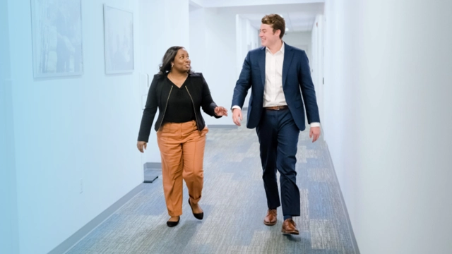 Two people walking down an office corridor