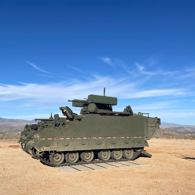 BAE Systems’ green Armored Multi-Purpose Vehicle (AMPV) Counter-Unmanned Aircraft System (C-UAS) prototype with desert mountain range in the background.