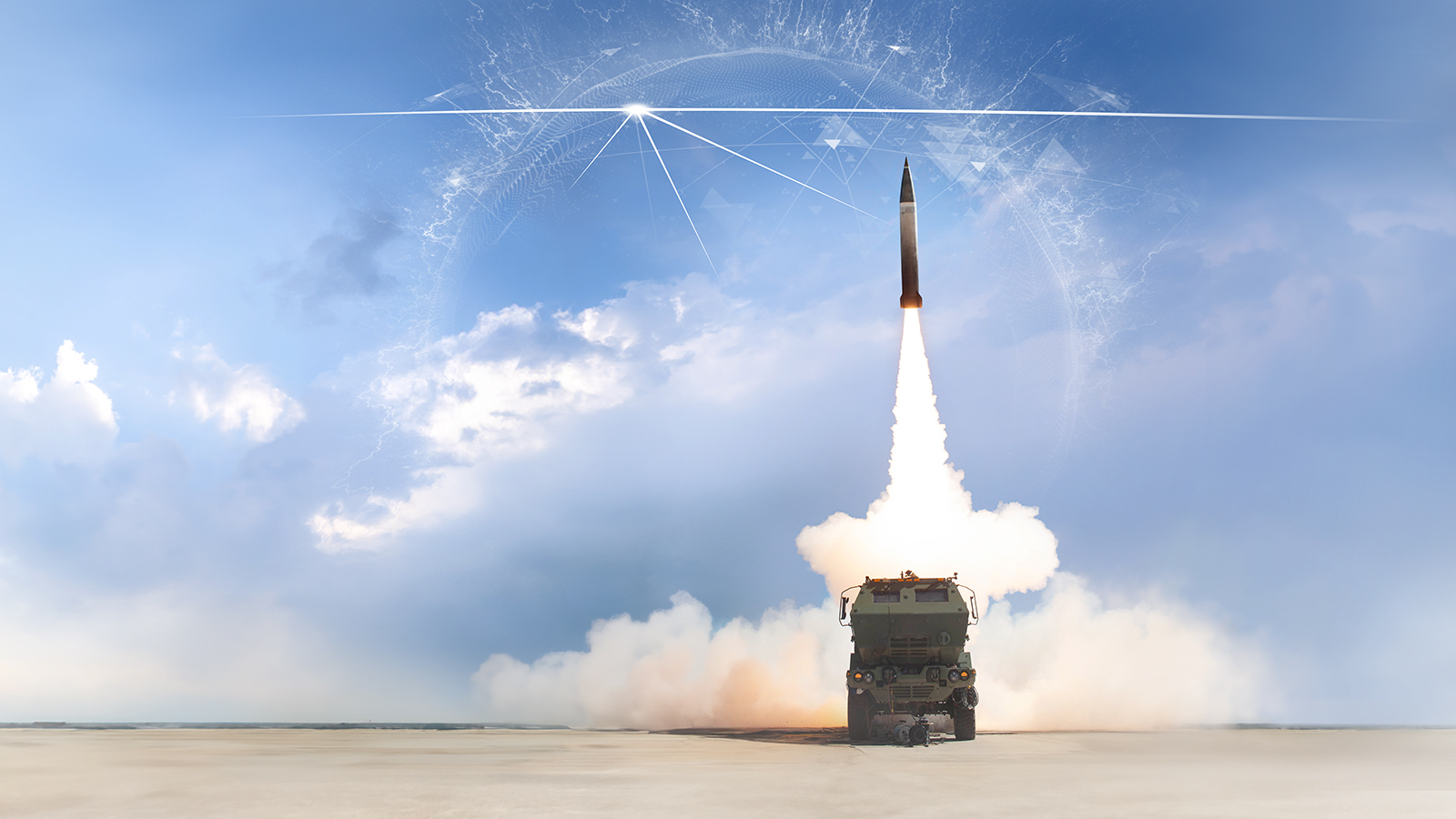 Military rocket in flight against blue sky with stream of smoke beneath it. Military vehicle at base of image.