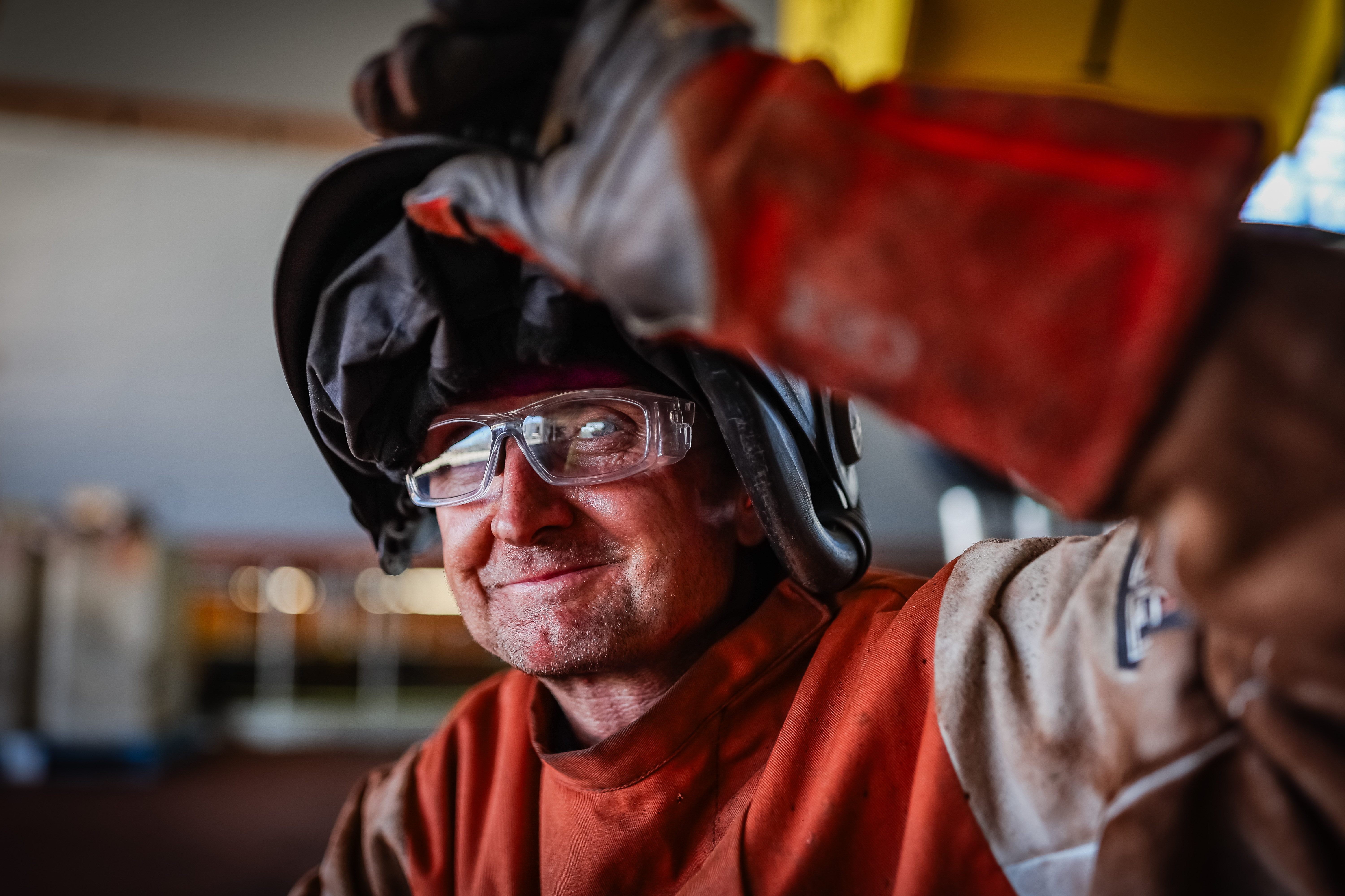 Man lifting visor of welder's helmet and protective gloves