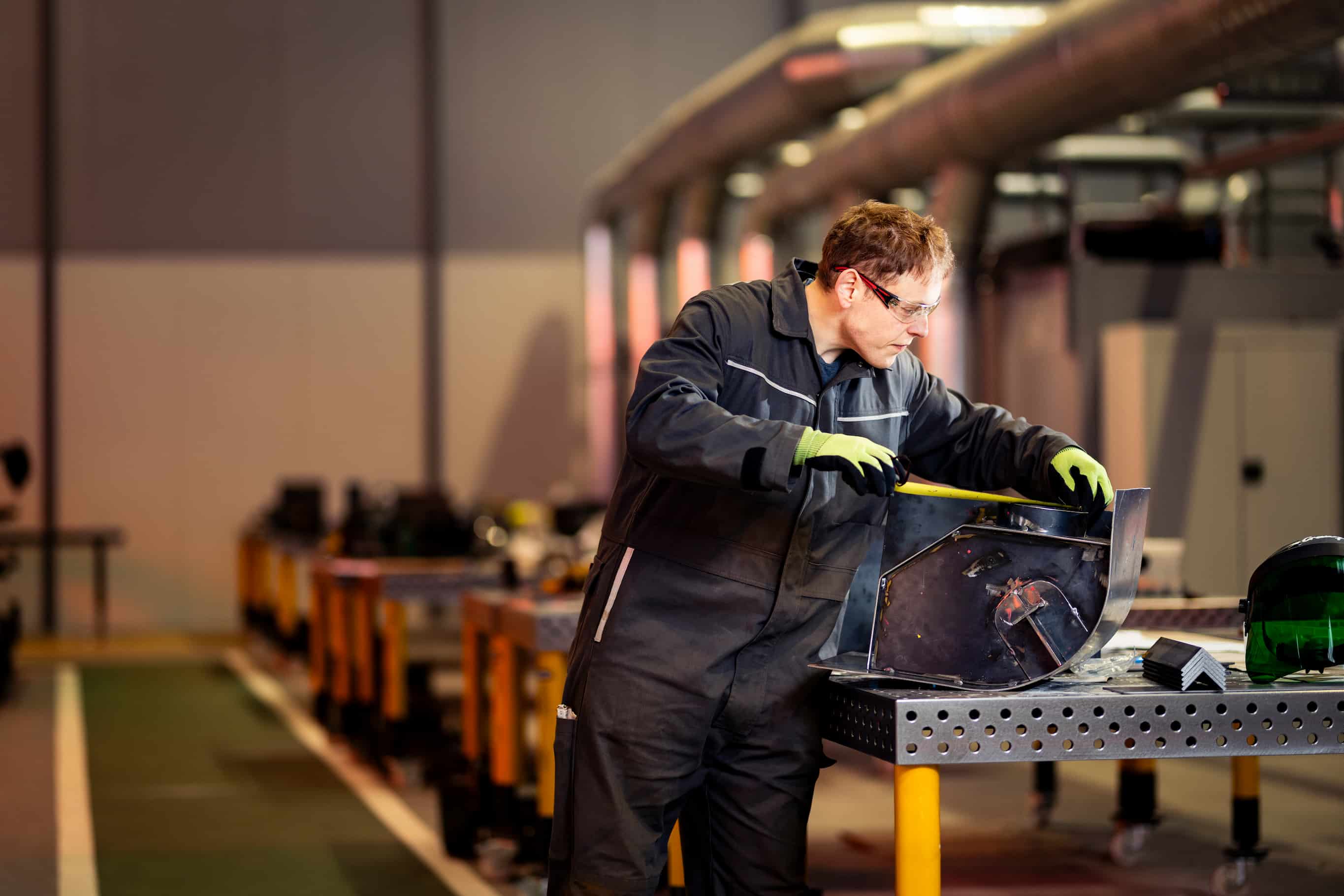 Employee preparing metal exterior in workshop