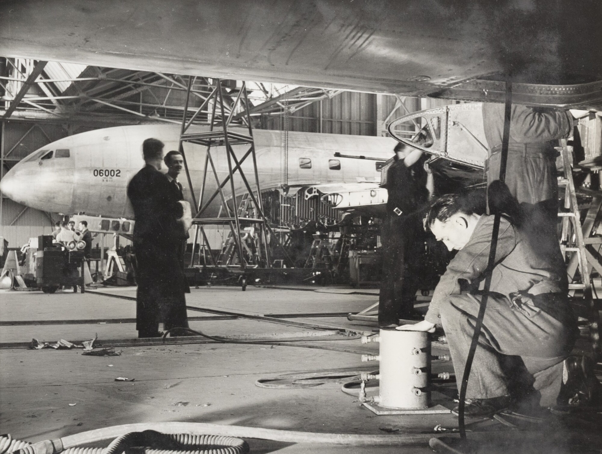 A de Havilland DH.106 Comet 1 under construction in an aircraft hangar, with workers in the foreground.