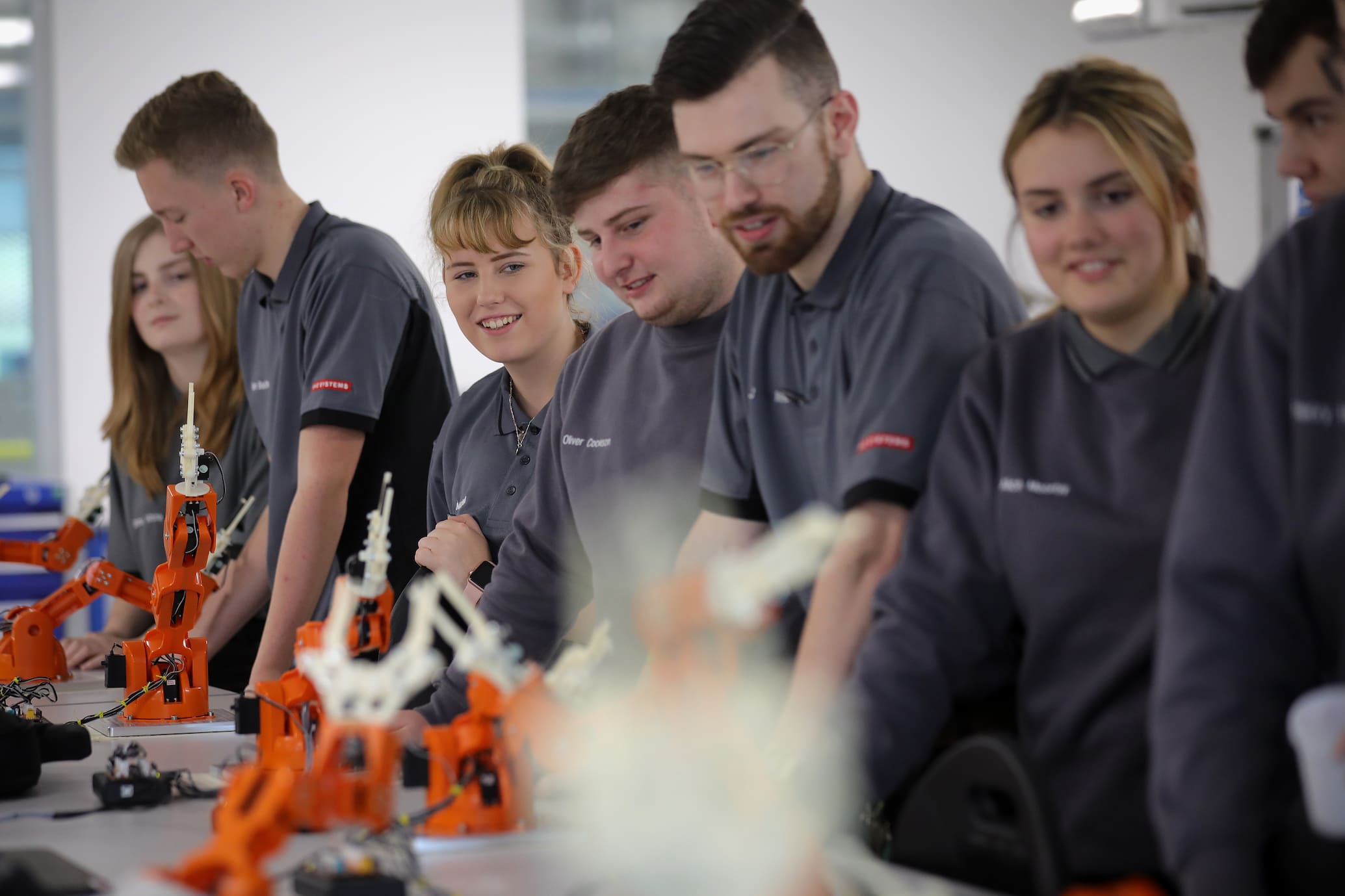 Group of young apprentices building robotic arm models