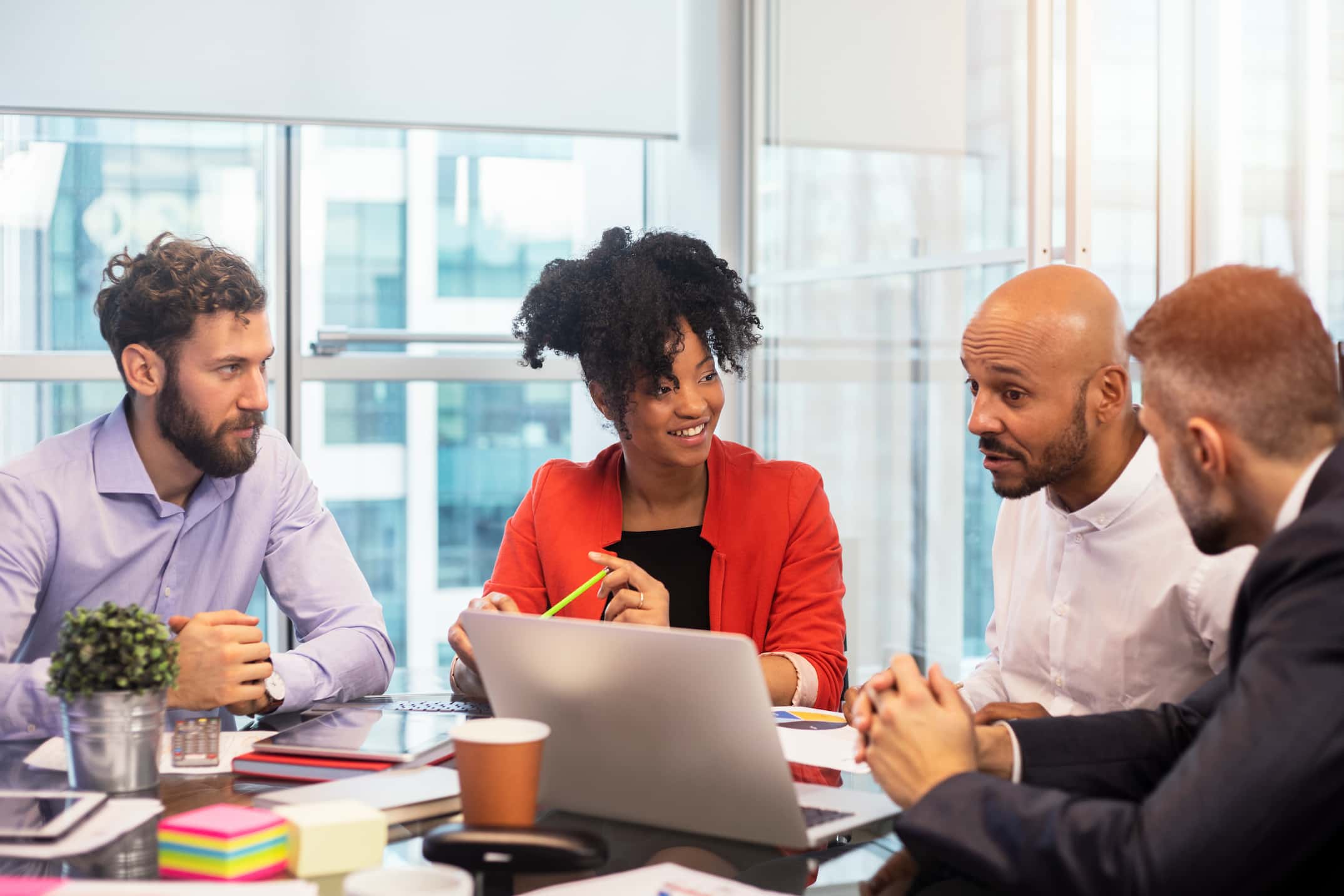 Colleagues sitting around a meeting table in a well-lit glass office