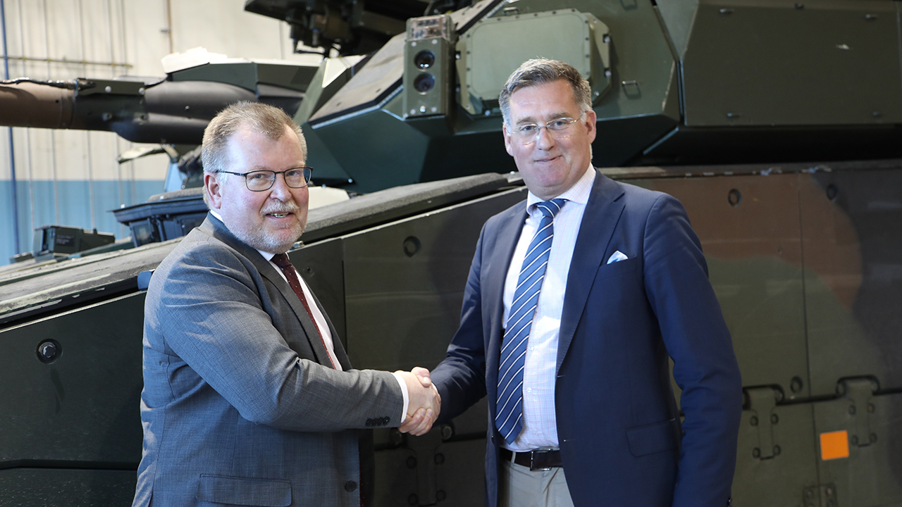 Tommy Gustafsson-Rask, Managing Director of BAE Systems Hägglunds, and Brigadier General Jonas Lotsne, Director of Land Systems, Swedish Defence Materiel Administration (FMV), shake hands in front of a CV90 during contract signing.