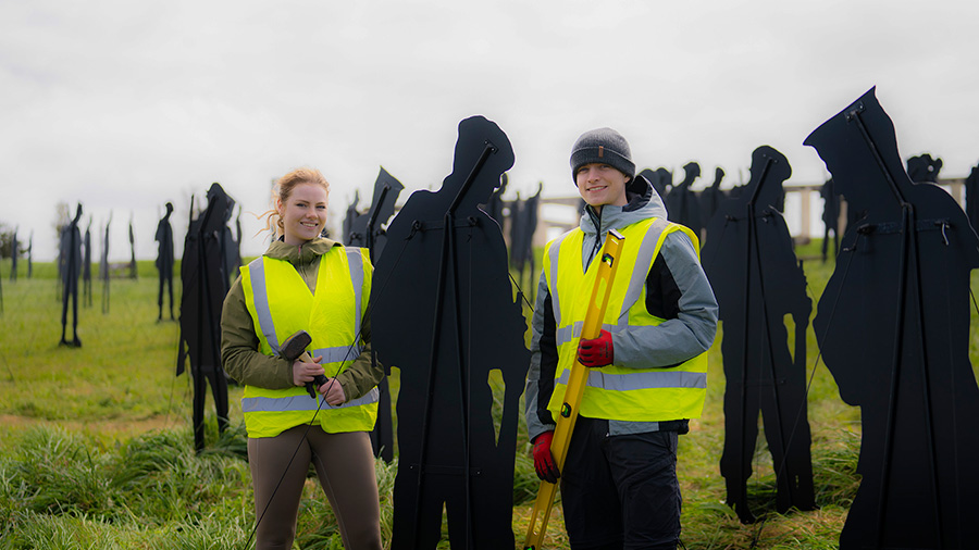 Two volunteers pose for a photo at the Standing with Giants installation between Gold Beach and the British Normandy Memorial in Ver-sur-Mer, France.