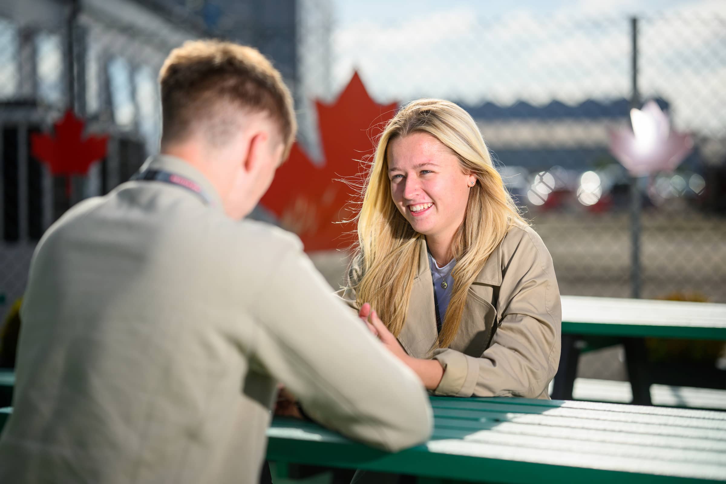 Colleagues talking at a table with a maple leaf sculpture in the background