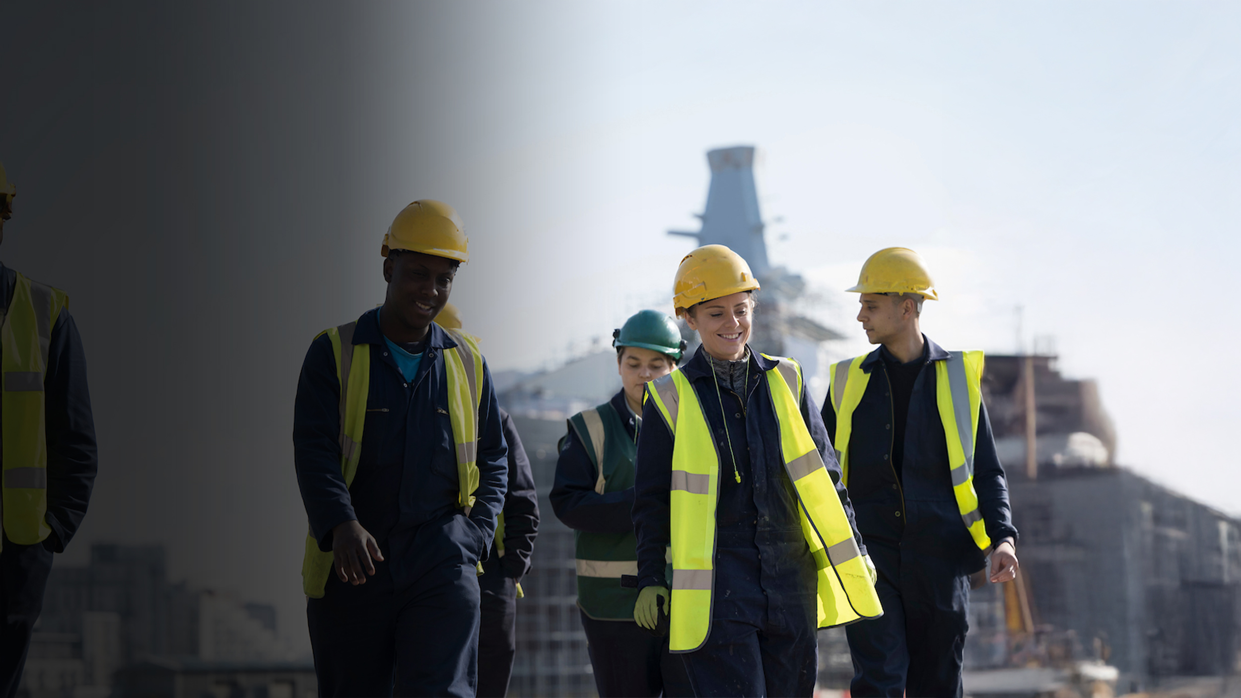 Colleagues in hardhats beside a navy ship