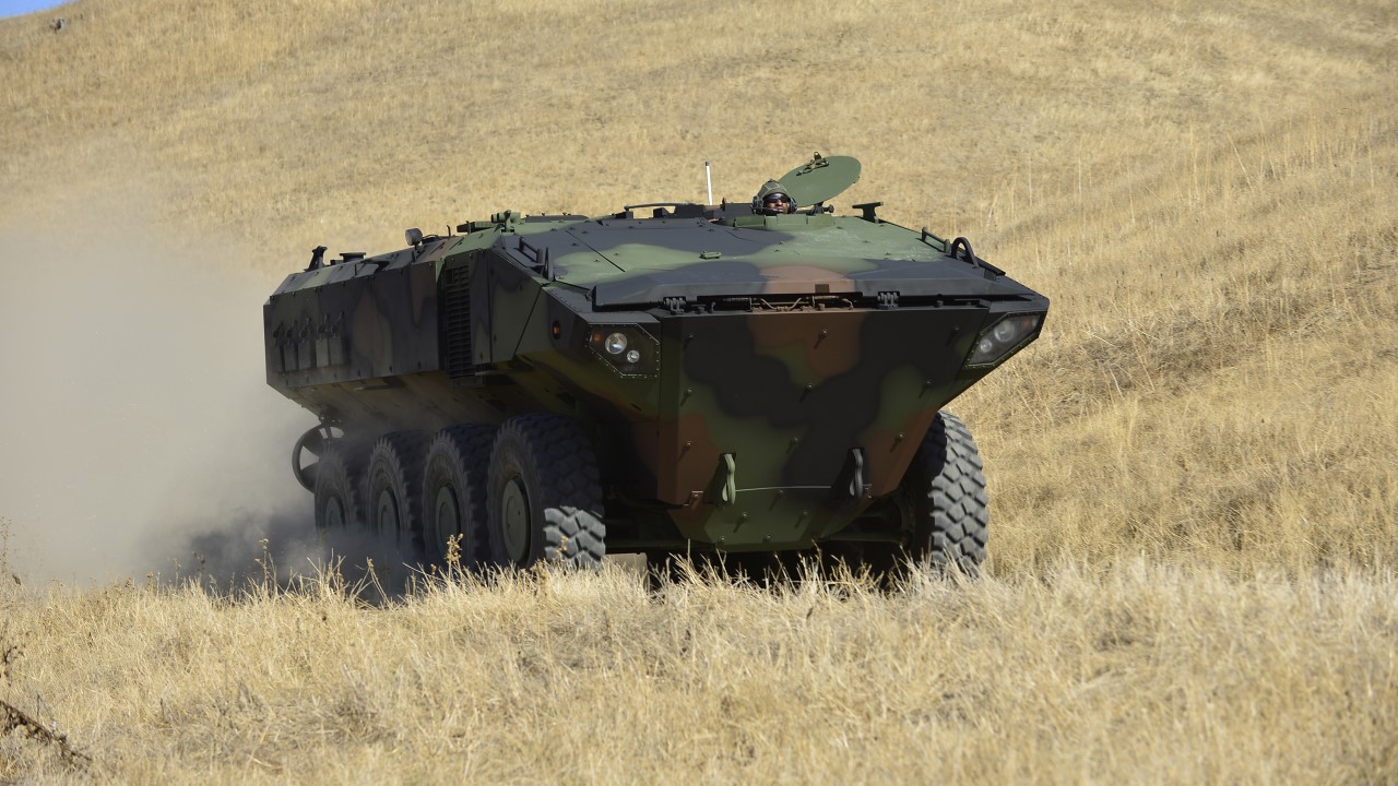 An Amphibious Combat vehicle driving through a field