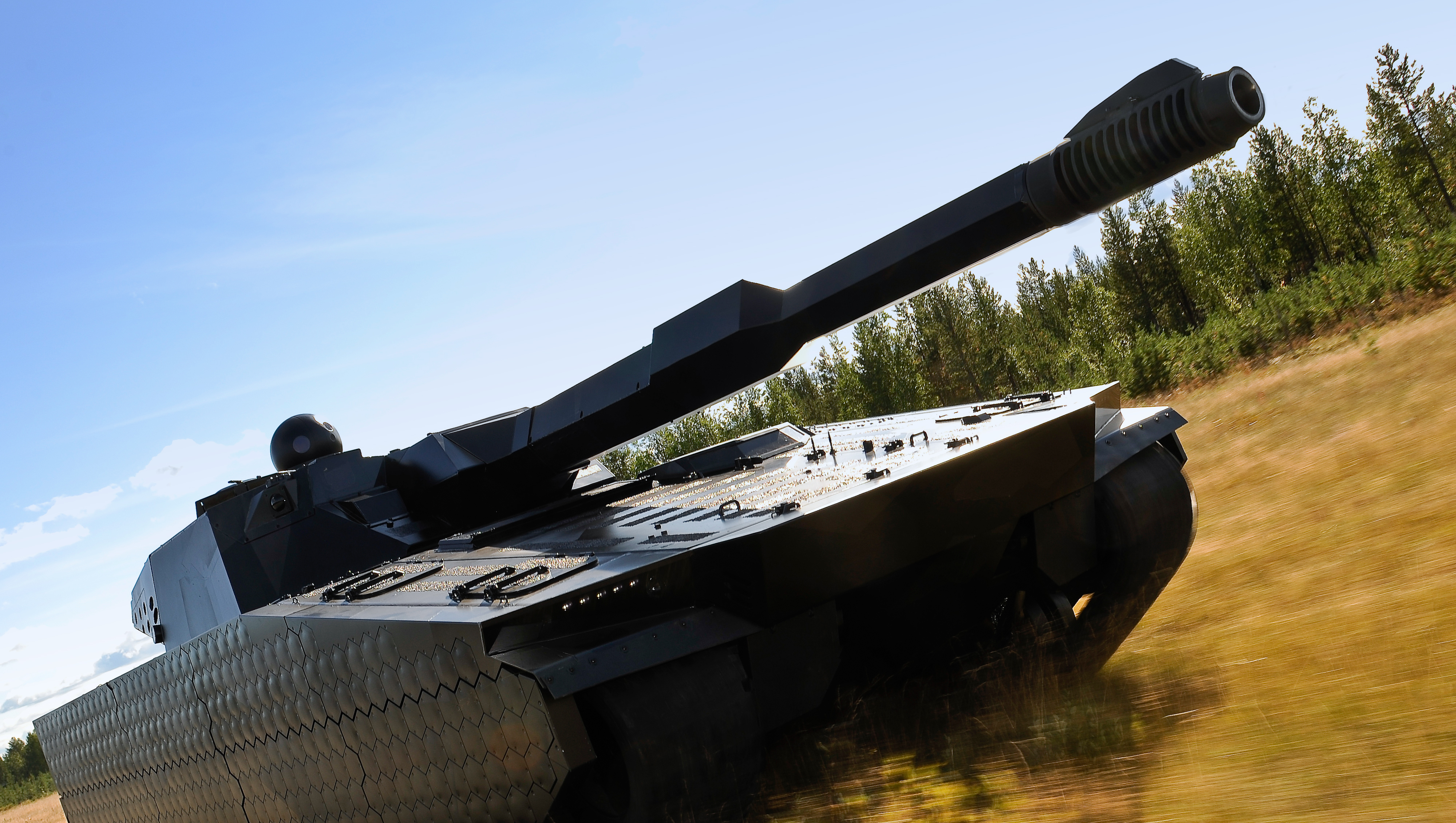 A black CV90120 driving through a field with trees in the background