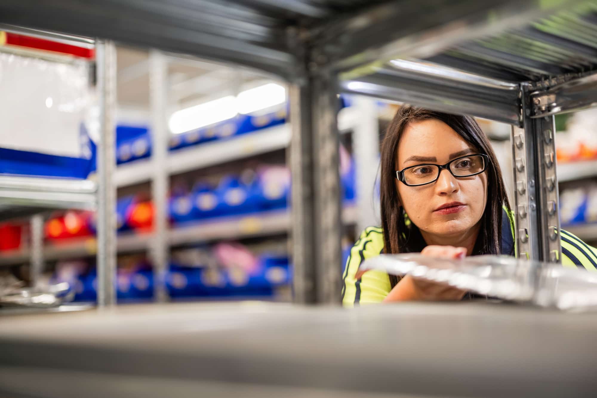 Female employee putting metal sheet away on shelf
