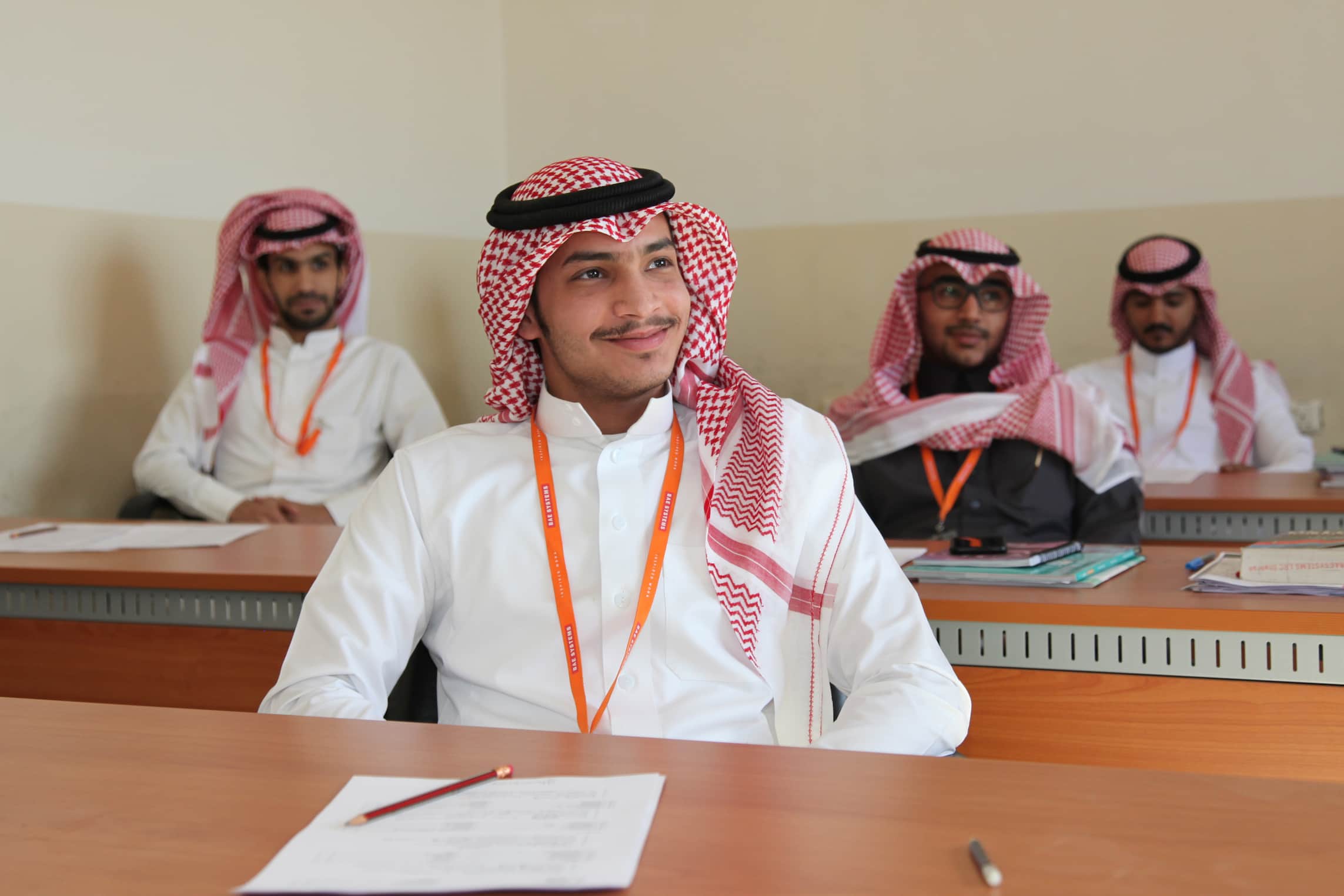Young male apprentices in shemagh scarves at desks with notes