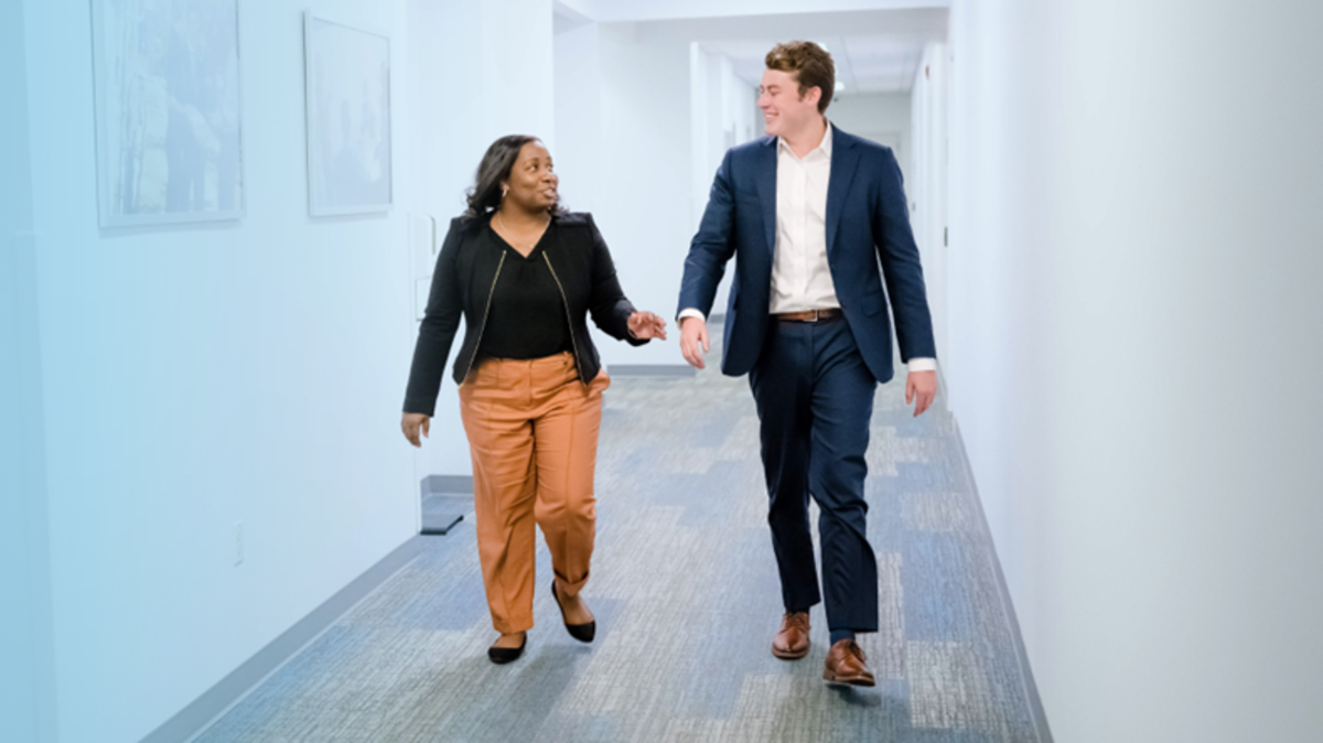 Two people walking down an office corridor