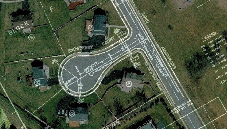 Aerial view of a residential cul-de-sac, with an overlay of street names, building and block identification, measurements, and other terrain data to indicate BAE Systems’ GPS Mapping & Charting Services capabilities. 