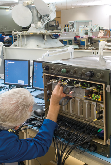 Image of person working on electronics inside a cabinet