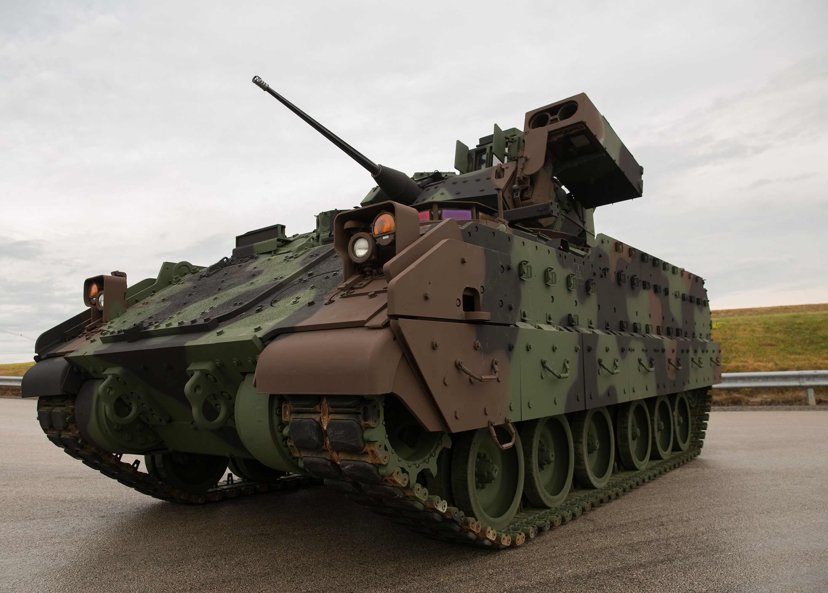 A parked brown, gray, and green camouflage Bradley Fighting Vehicle