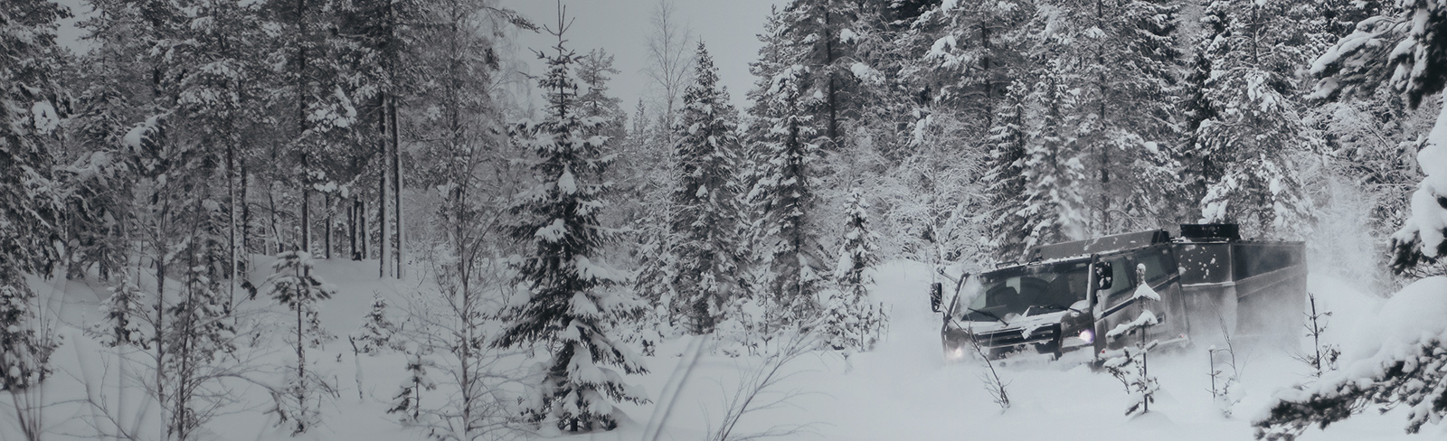 A Beowulf vehicle viewed from the front as it drives through snow-covered woods