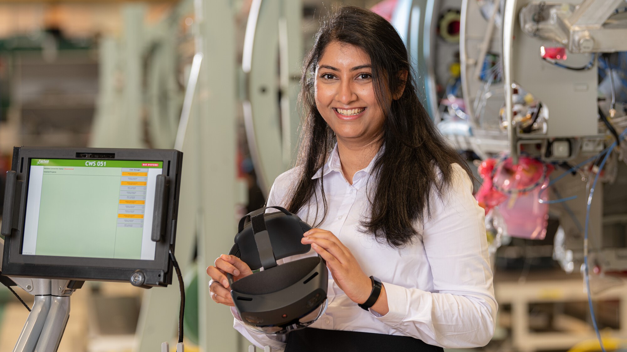 Neelofar next to a screen, holding a smart gantry headset