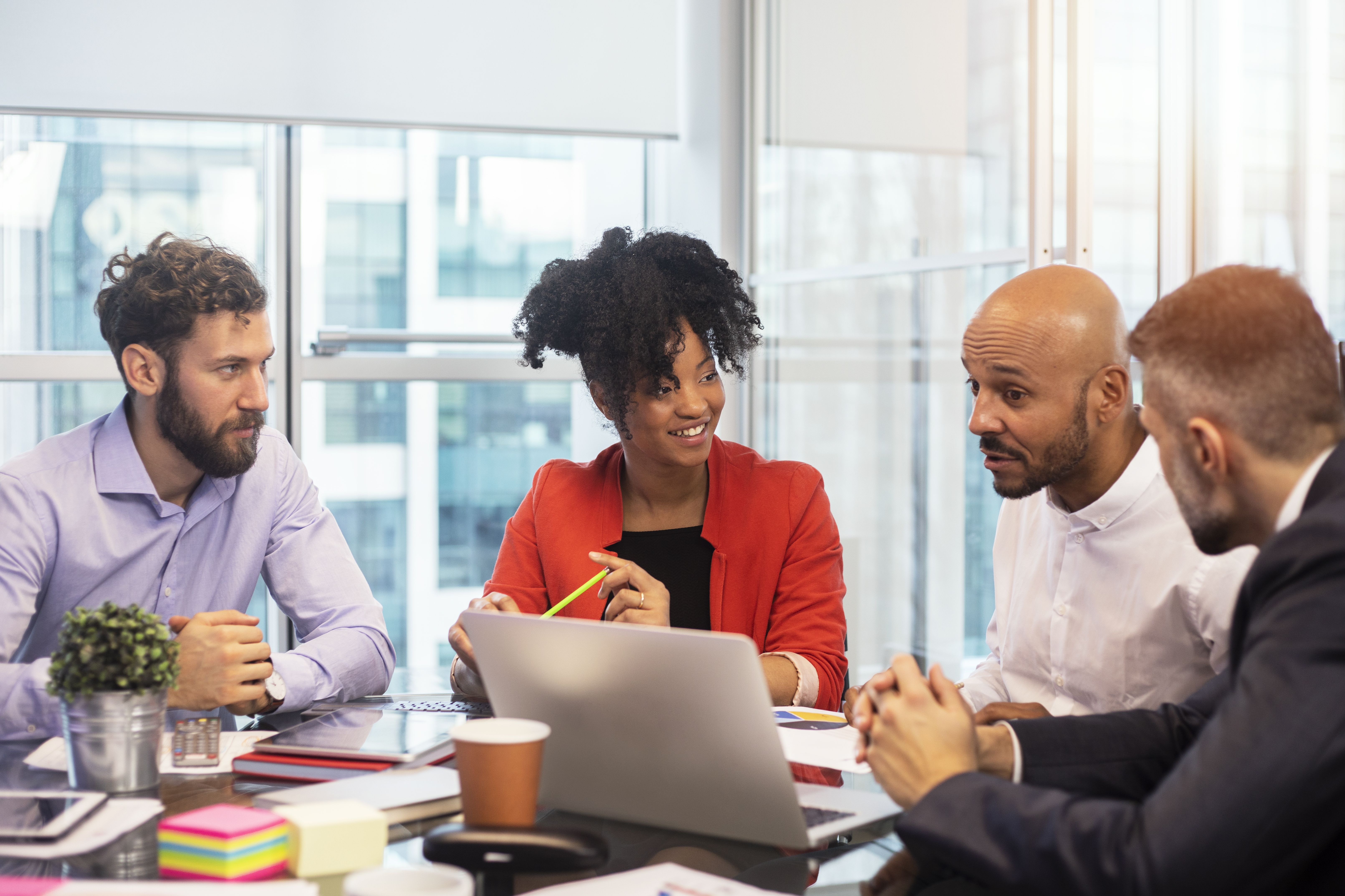 Colleagues talking around a table in a well-lit glass office
