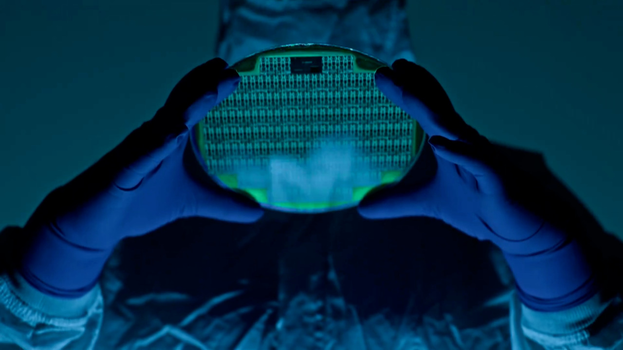 Scientist in cleanroom suit holding a glowing silicon wafer with integrated circuits, representing advanced microelectronics manufacturing and semiconductor technology.