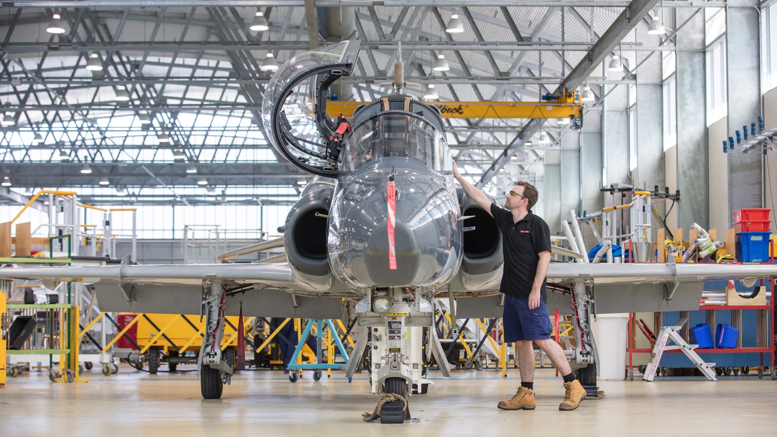 A BAE Systems aircrew technician beside a Hawk aircraft