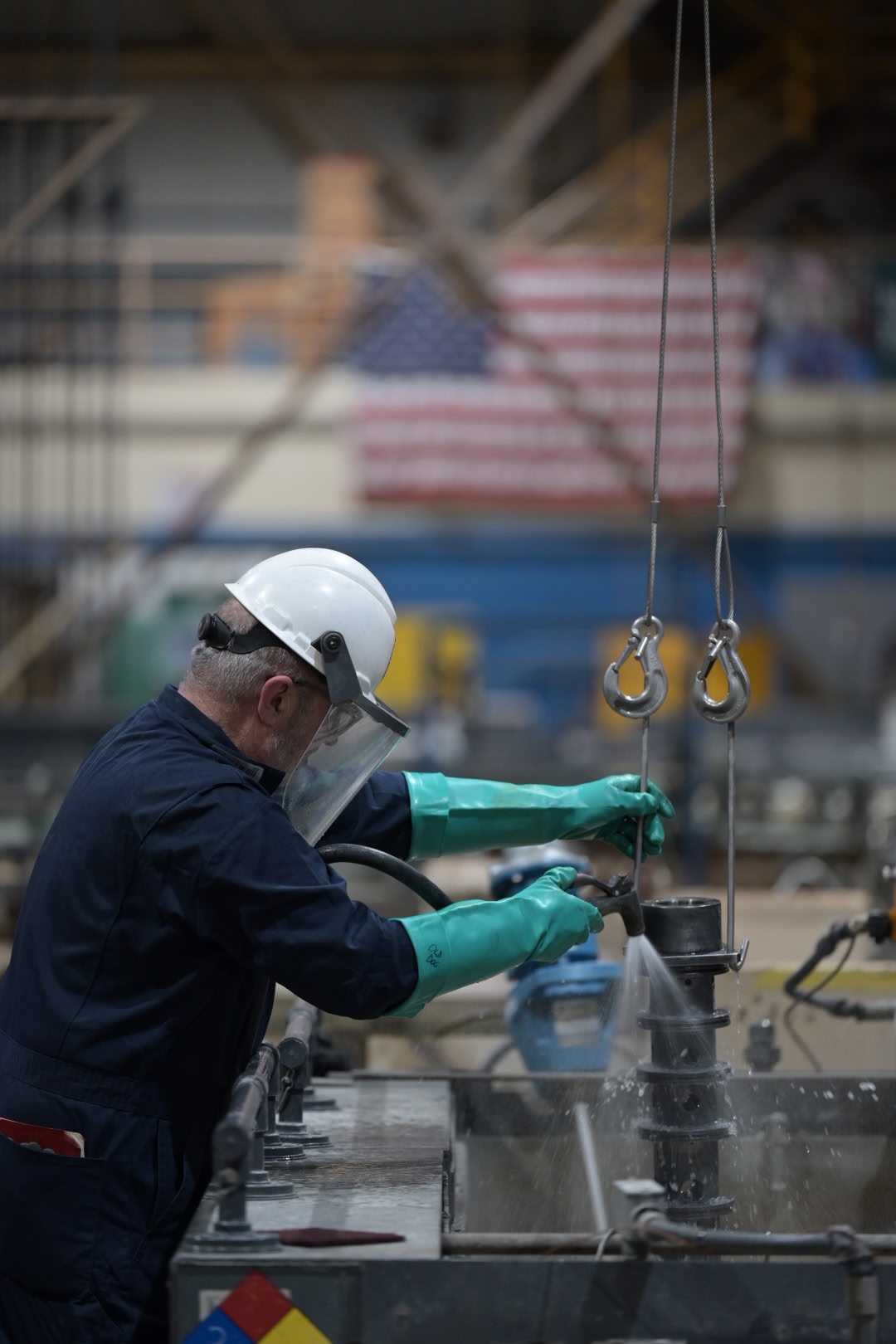 A worker prepares material for production with an American flag hanging behind him