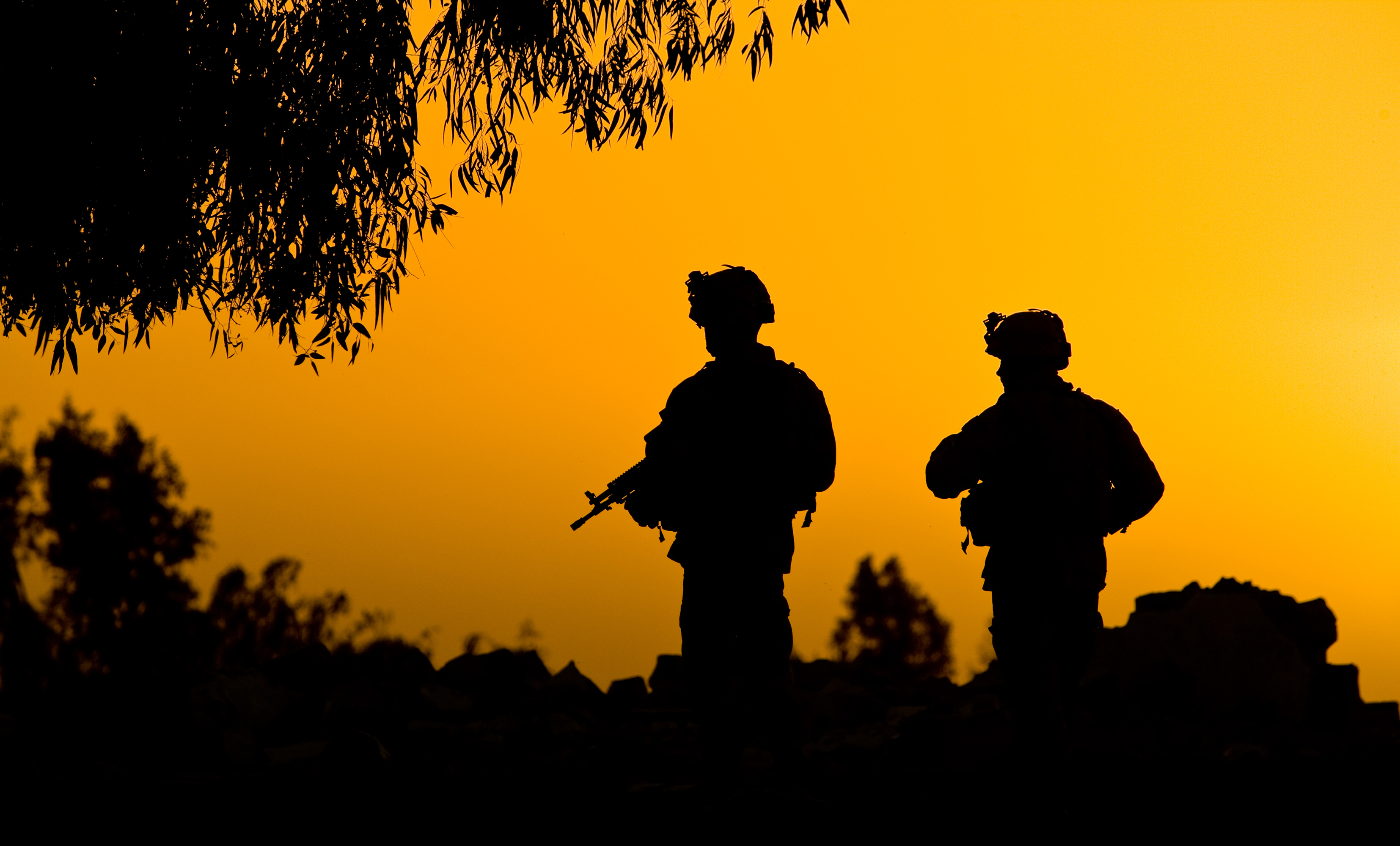 Silhouette of two soldiers against an orange sky