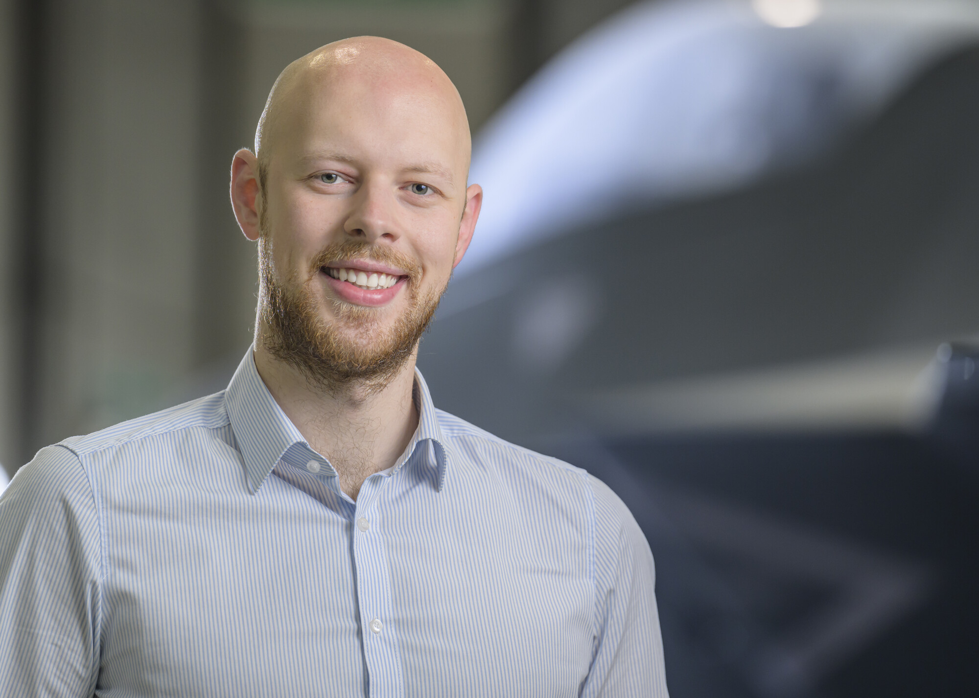 Allan looking at the camera smiling with the Tempest concept model in the background