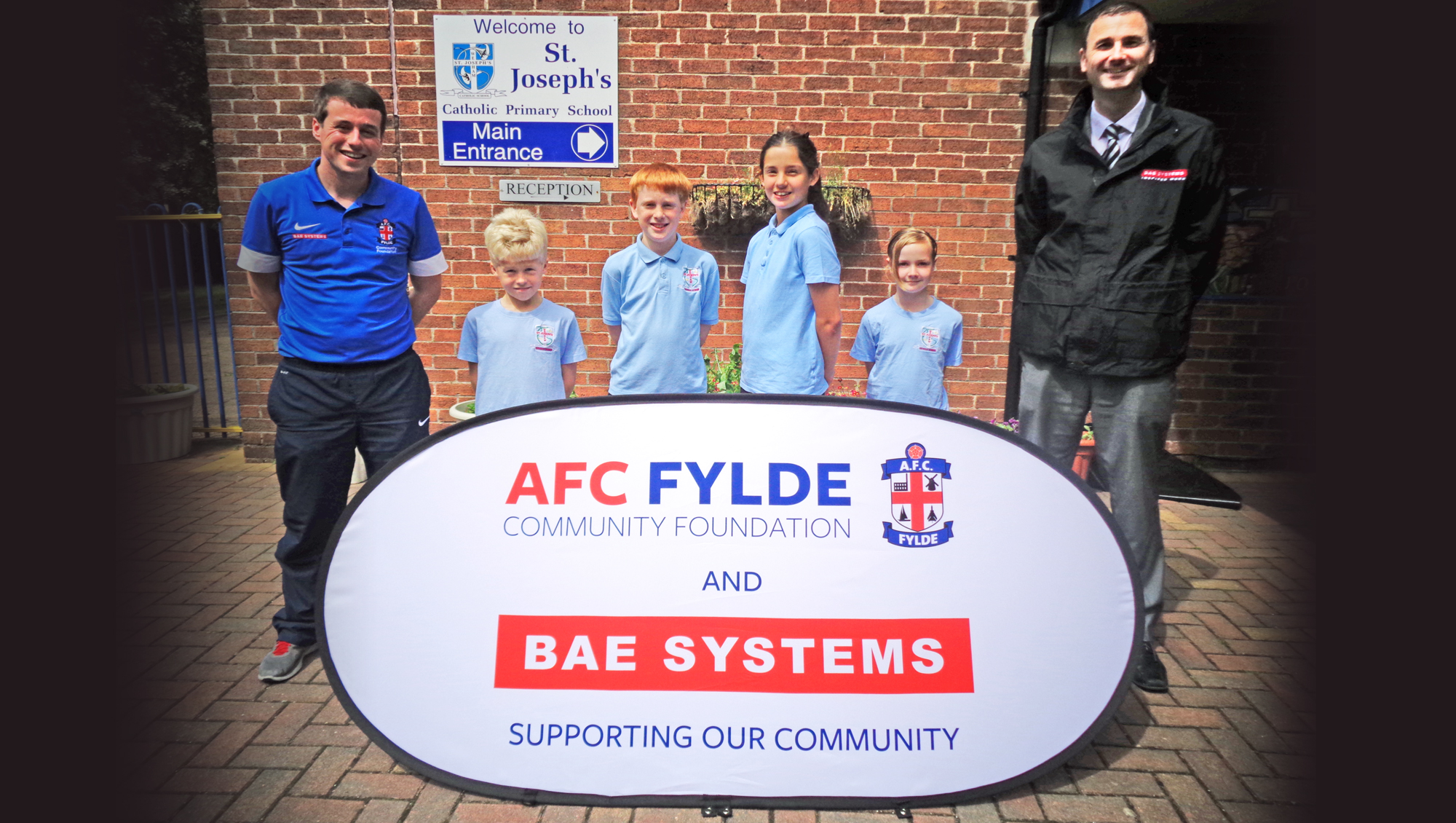 Tom Hutton (AFC Fylde) and Paul Earnshaw (BAE Systems) with children from St Jospeh's School Wesham