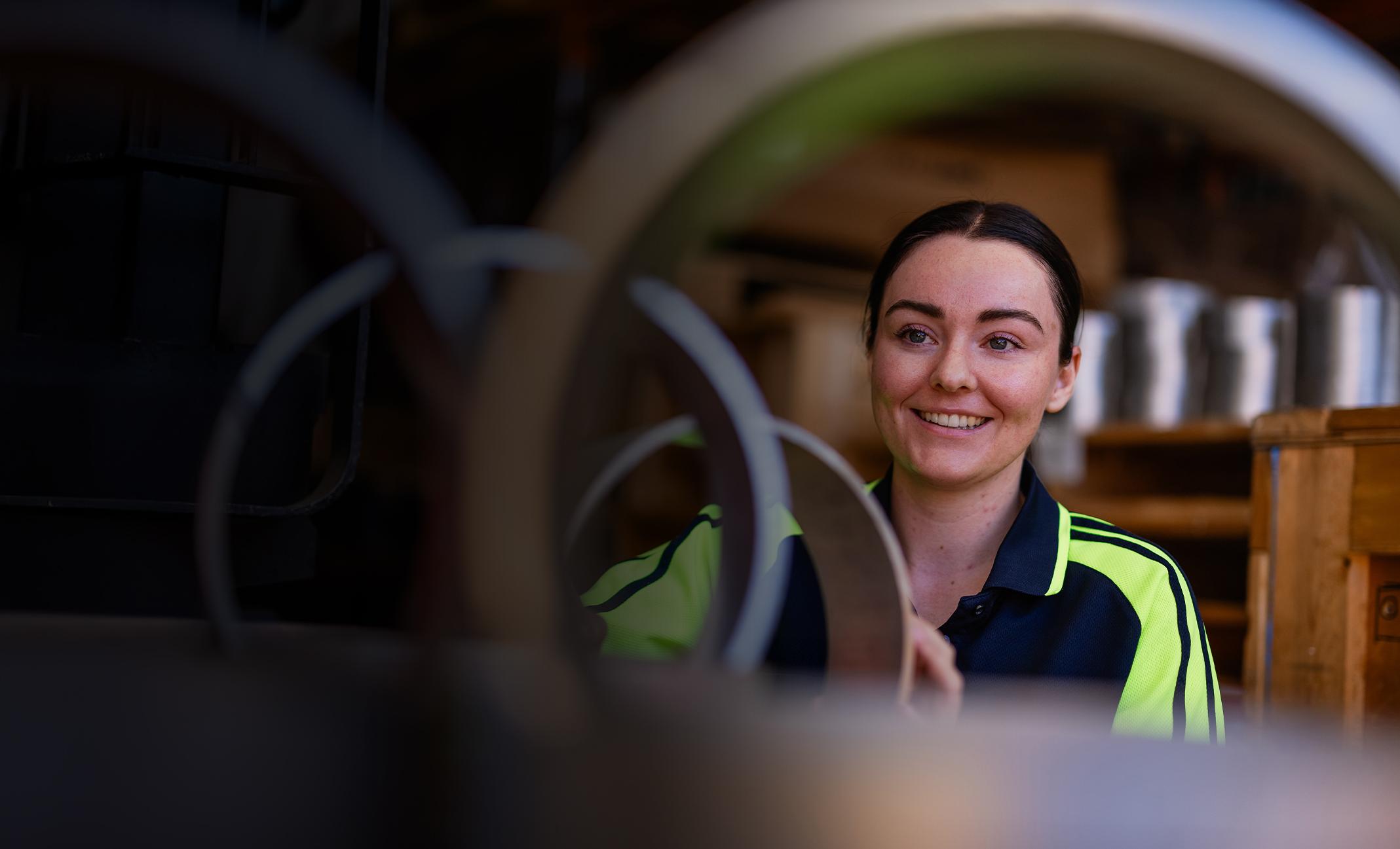 Young woman employee smiling as she works with metal