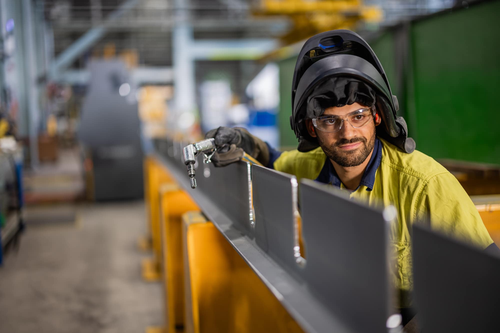 Young man in welder's mask looks towards the camera