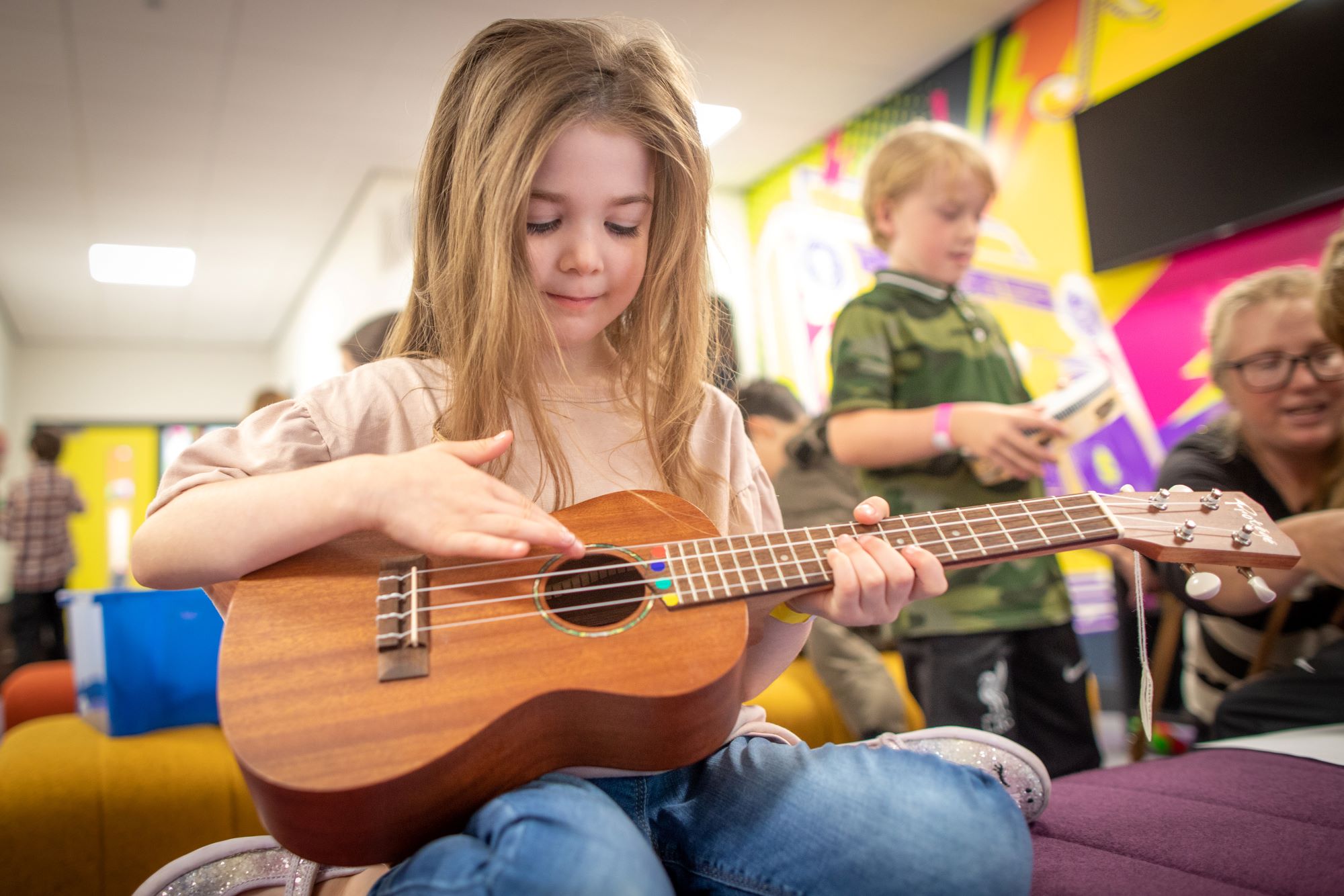 A young girl plays an acoustic guitar