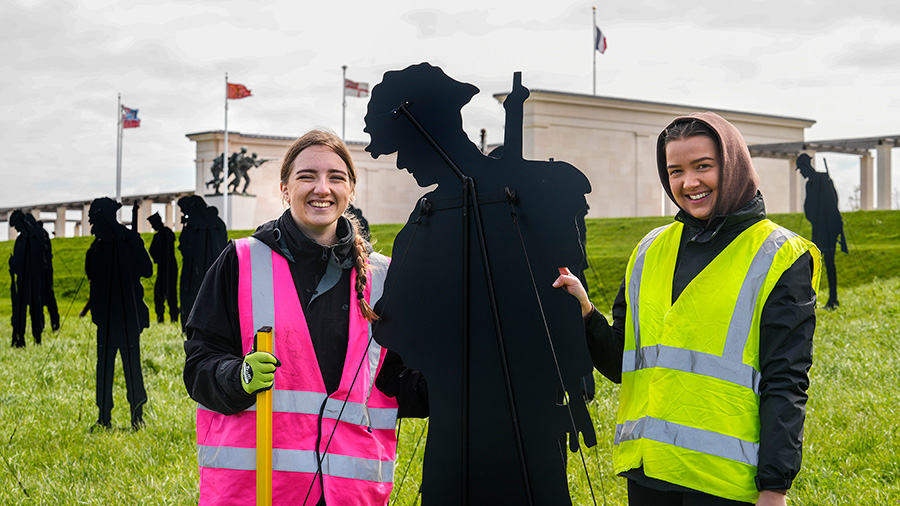 Two volunteers pose for a photo at the Standing with Giants installation between Gold Beach and the British Normandy Memorial in Ver-sur-Mer, France.