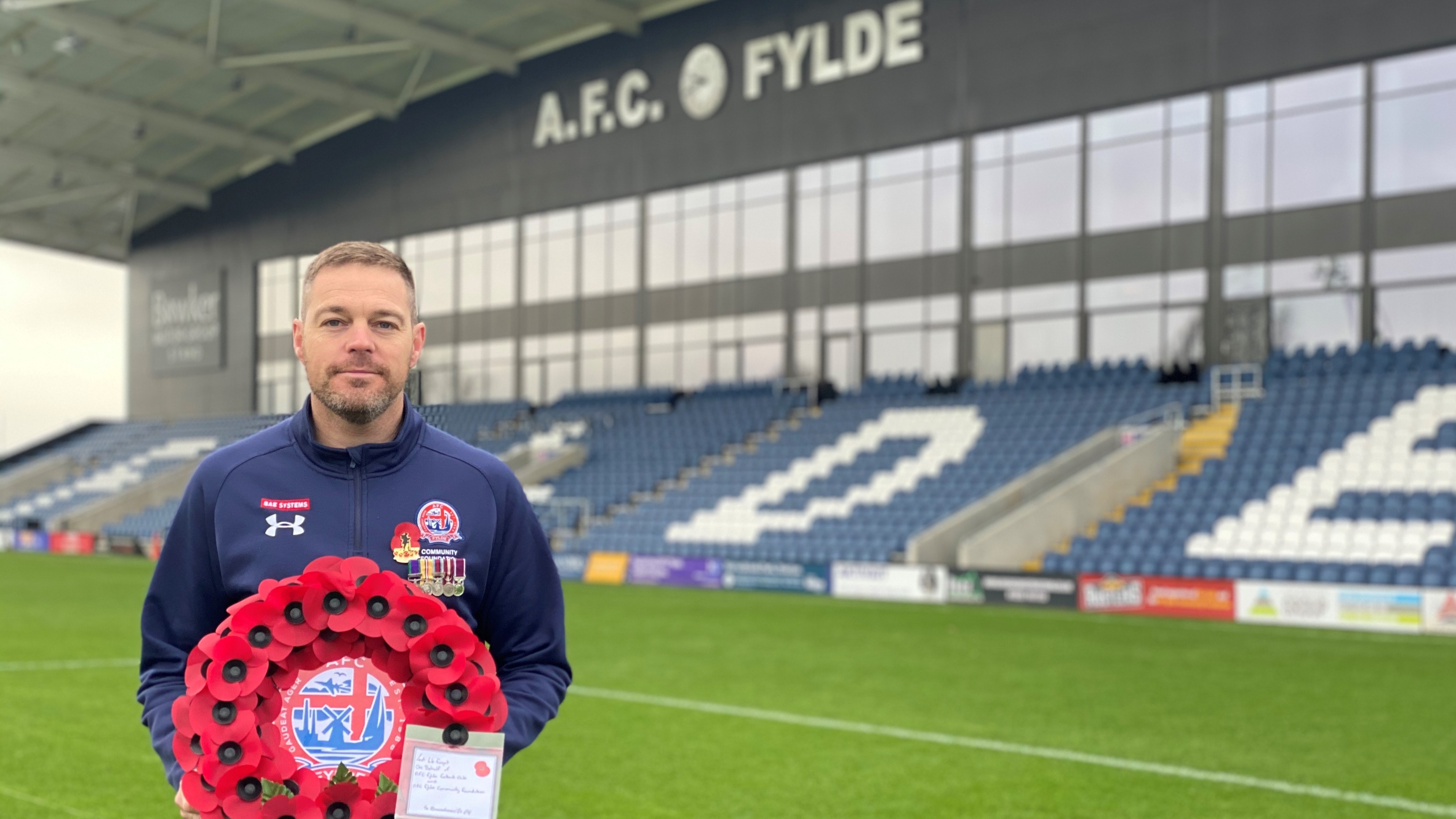 Lee Geraghty, AFC Fylde Armed Forces Support Officer with remembrance wreath in AFC Fylde stadium