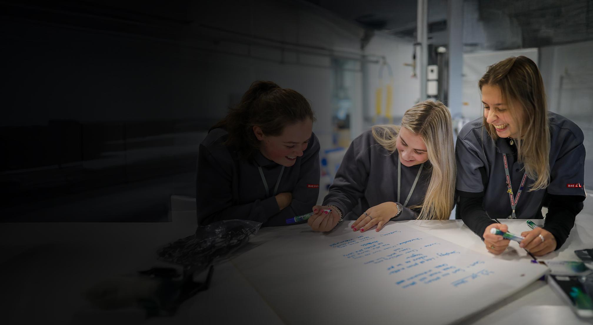 Apprentices laughing as they make notes on a writing pad