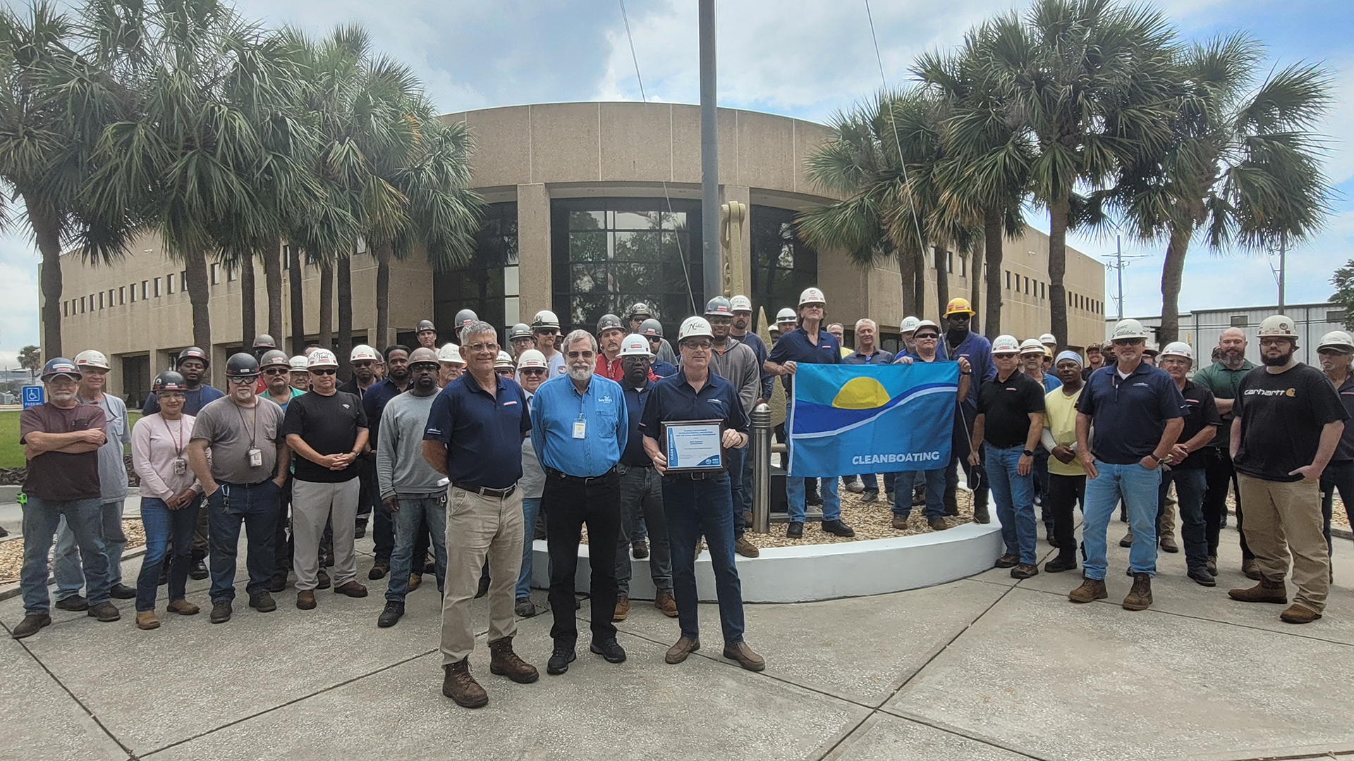 Jacksonville Ship Repair’s General Manager Tim Spratto & Environmental Manager John Nist & David Fuller (center), the FDEP Northeast District Clean Boating Coordinator stand in front of shipyard employees for the presentation of the Clean Boatyard award