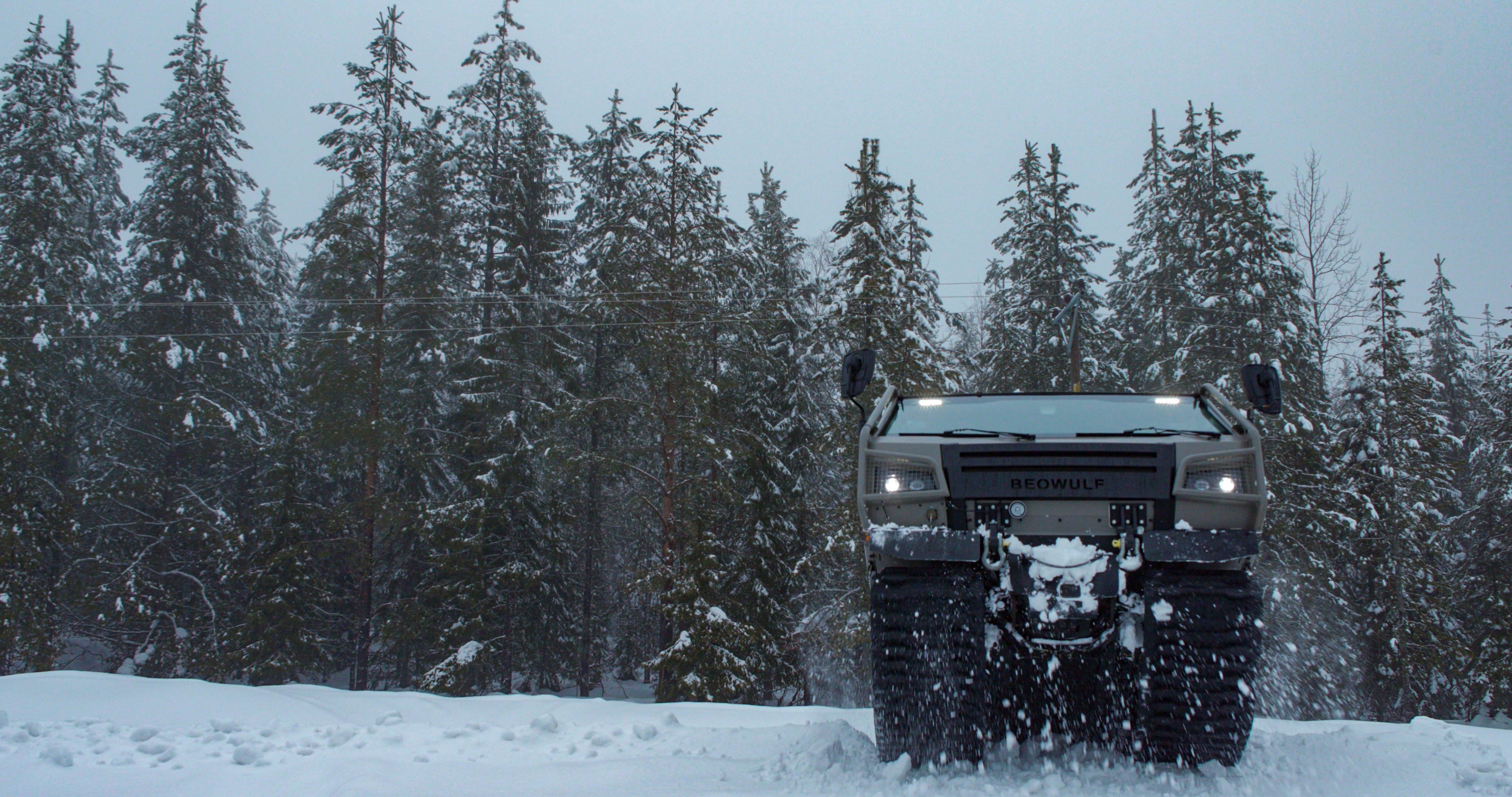 Beowulf vehicle driving towards the camera in a snowy forest