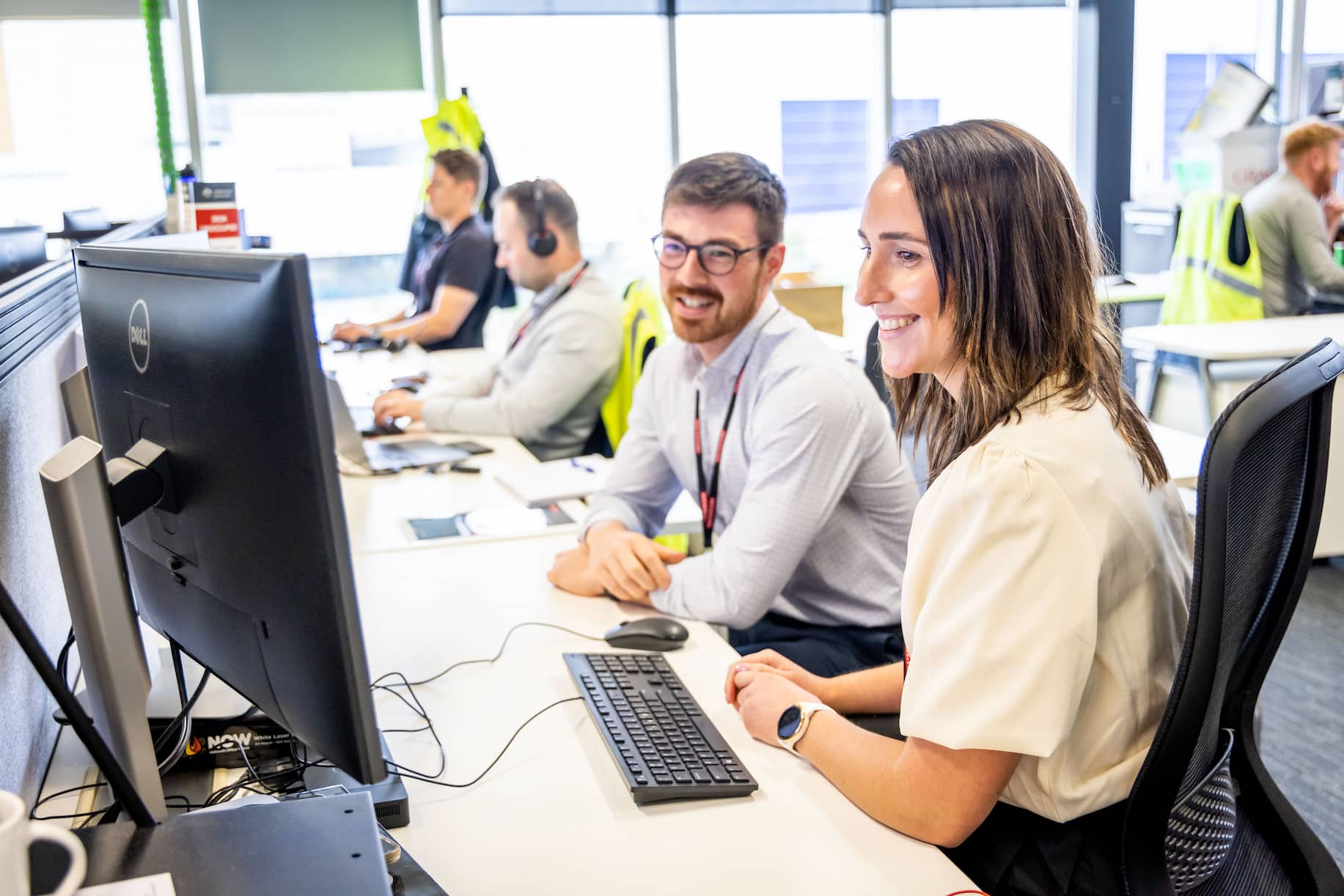 Colleagues at a row of desks smiling at each other