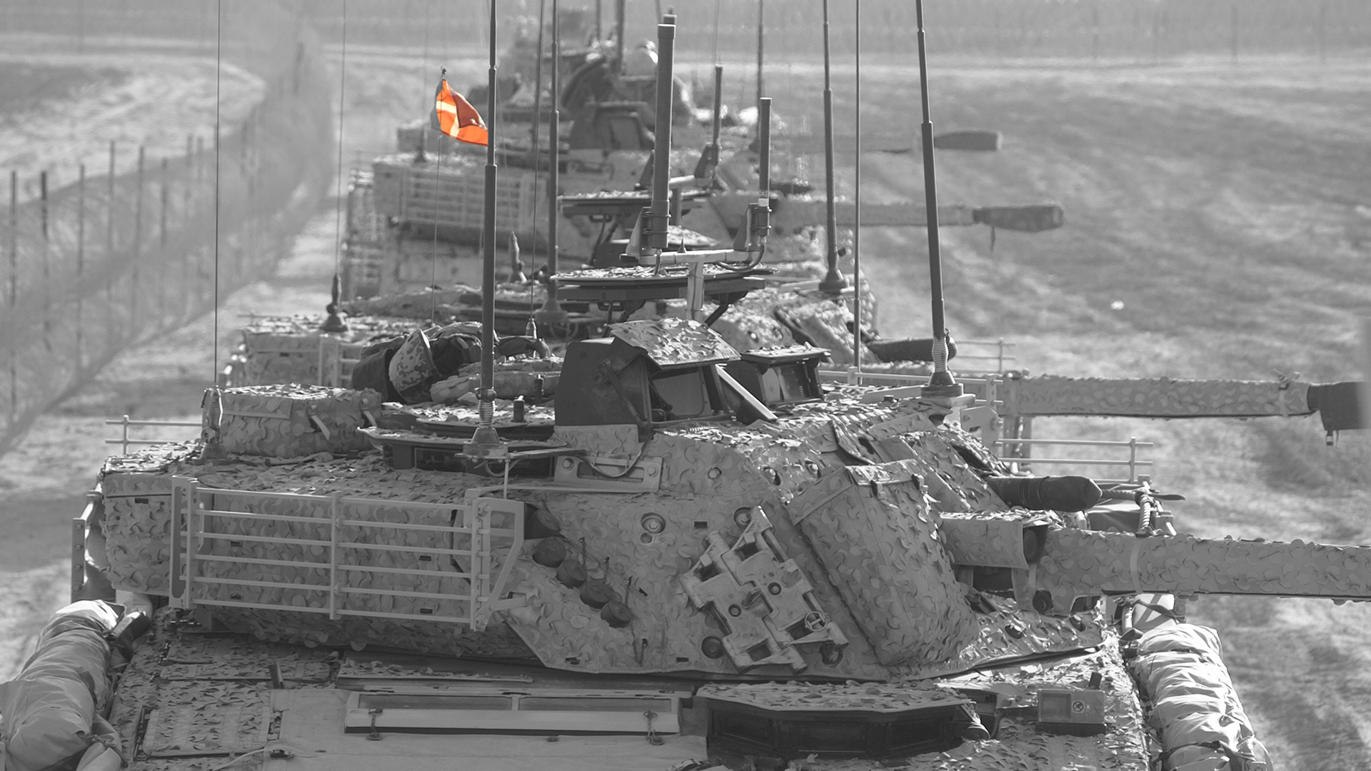 A black and white image of a lineup of CV90 vehicles, with the Danish flag in color