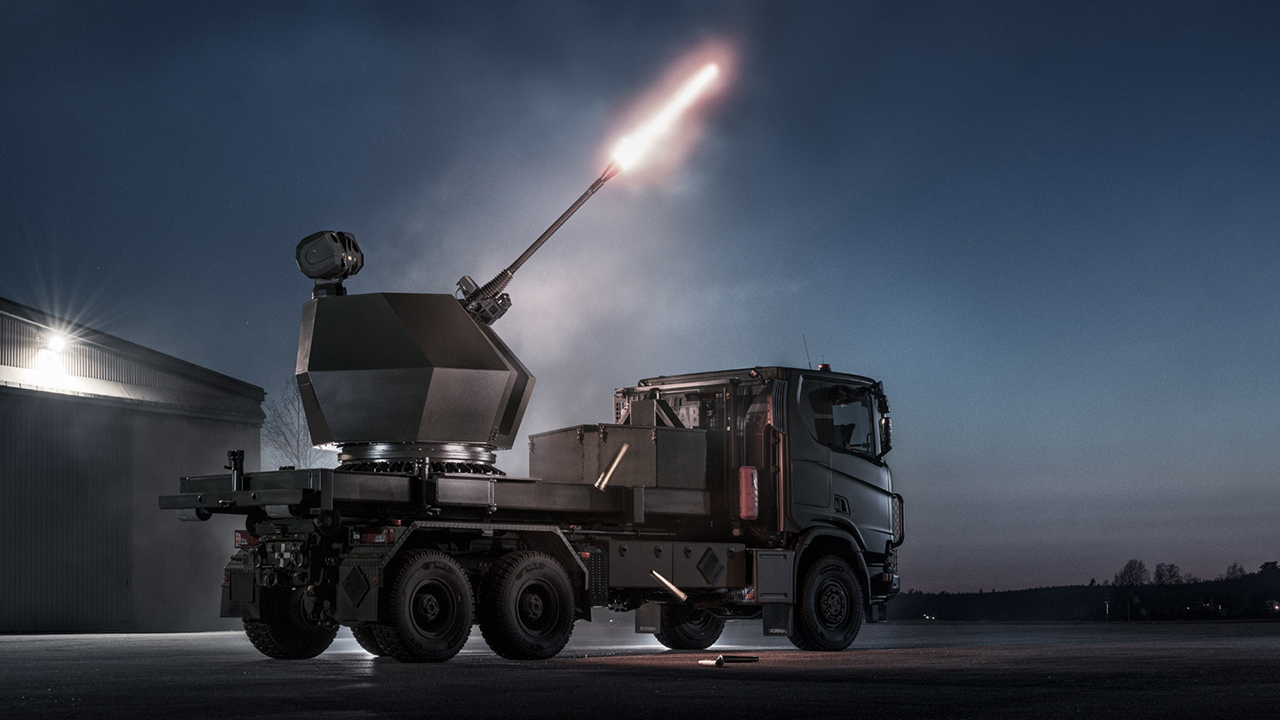A parked TRIDON vehicle firing at night, illuminated by a spotlight