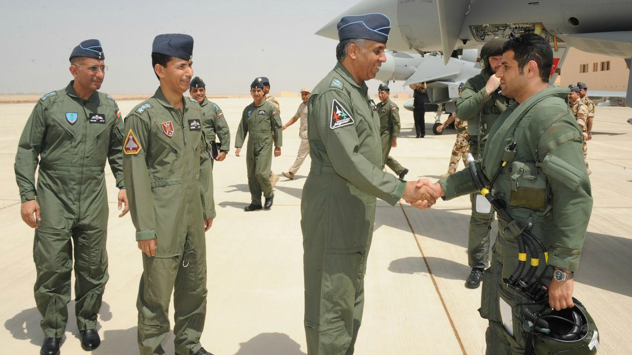 Omani Typhoon pilot shakes hands with Omani airforce leader. Typhoon aircraft in the background