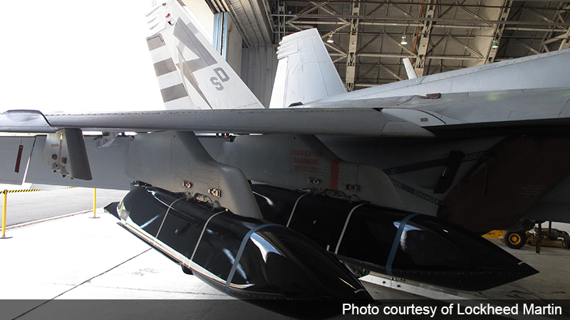 A fighter aircraft with two LRASM stealth missiles sits in a hangar