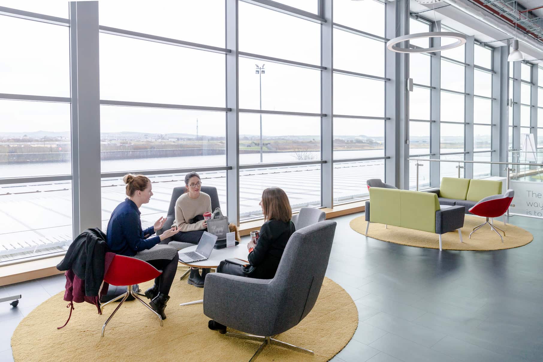 Three employees talking in modern office auditorium 