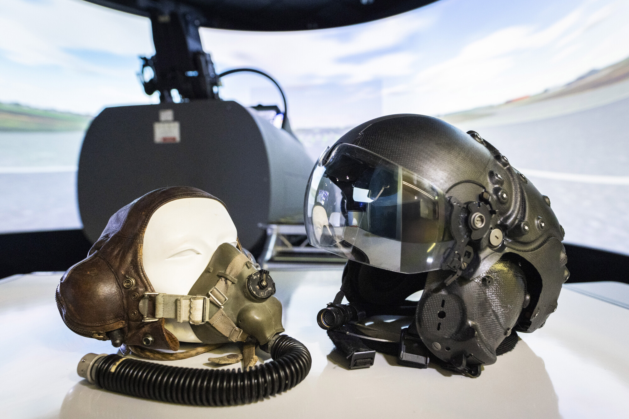 a leather helmet next to a striker helmet, showing the evolution of helmet technology over the past 100 years