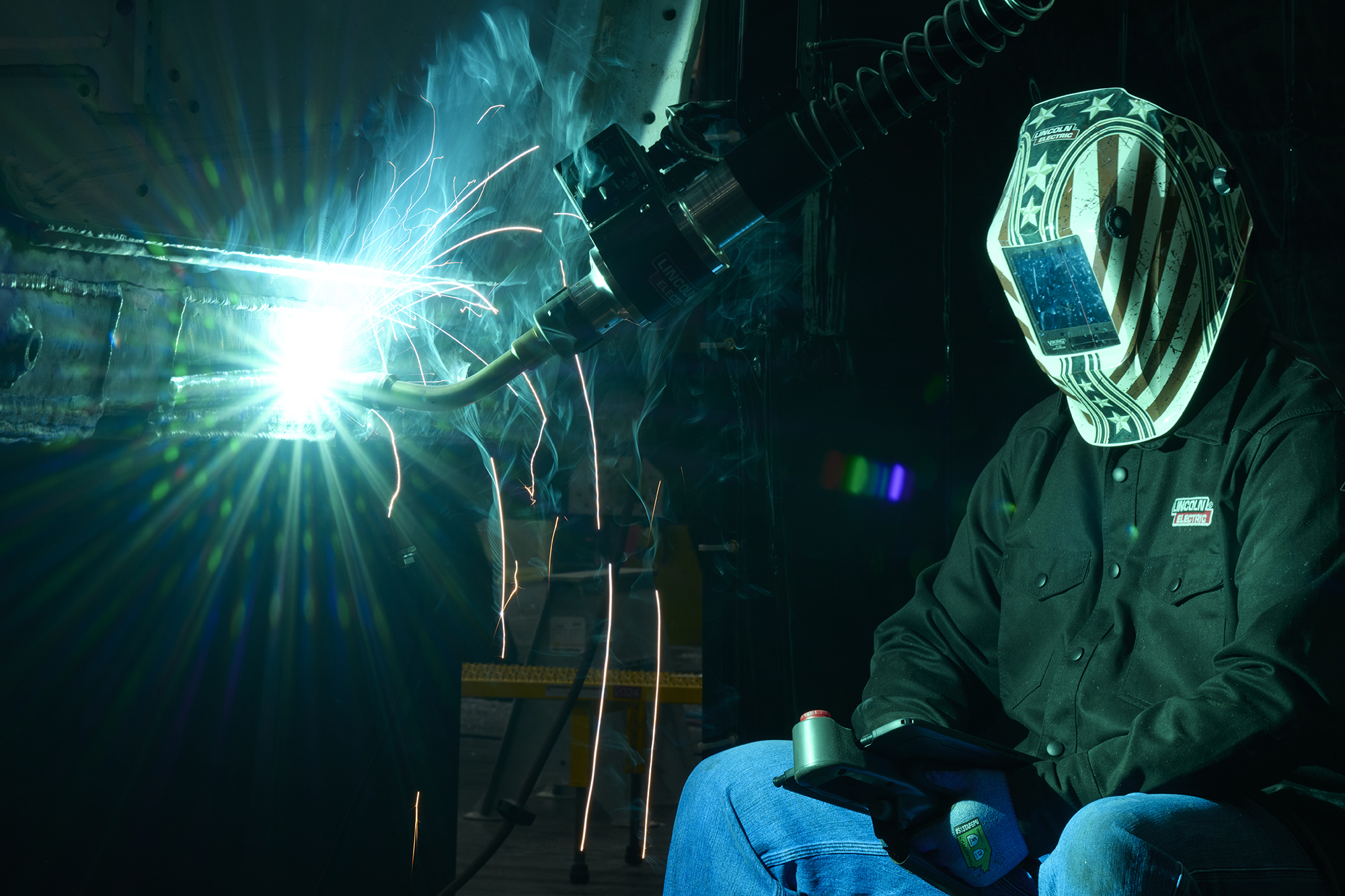 A welder with an American flag mask as blue sparks fly