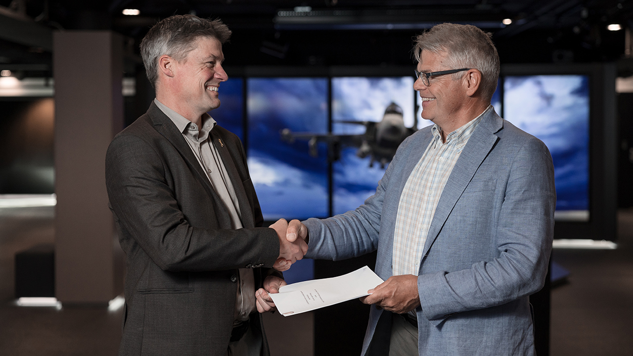 Representatives from BAE Systems and Saab shake hands