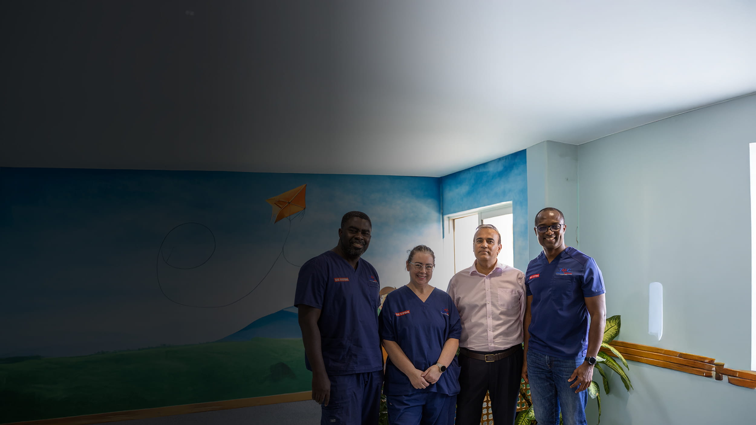 Group of employees in BAE Systems uniforms smiling at camera