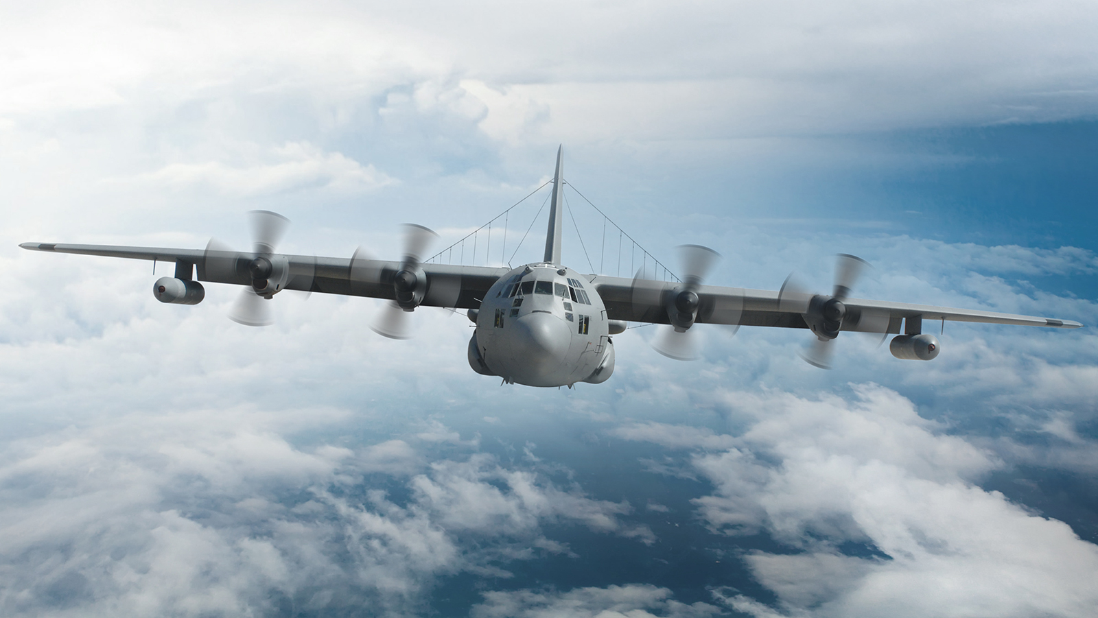 Gray EC-130 flying above clouds facing camera head-on