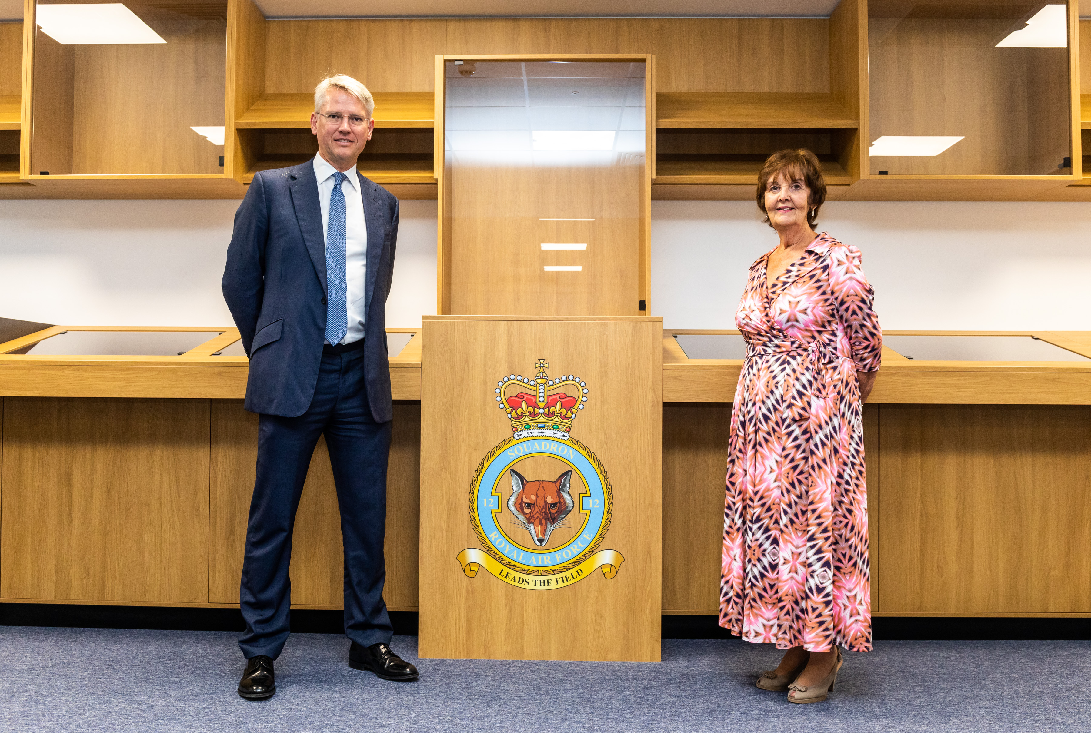 Man and woman stood in front of plaque displaying 12 Squadron logo