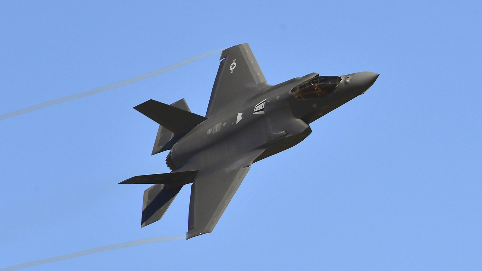  An F-35 Lightning II fighter jet flies across an azure sky.